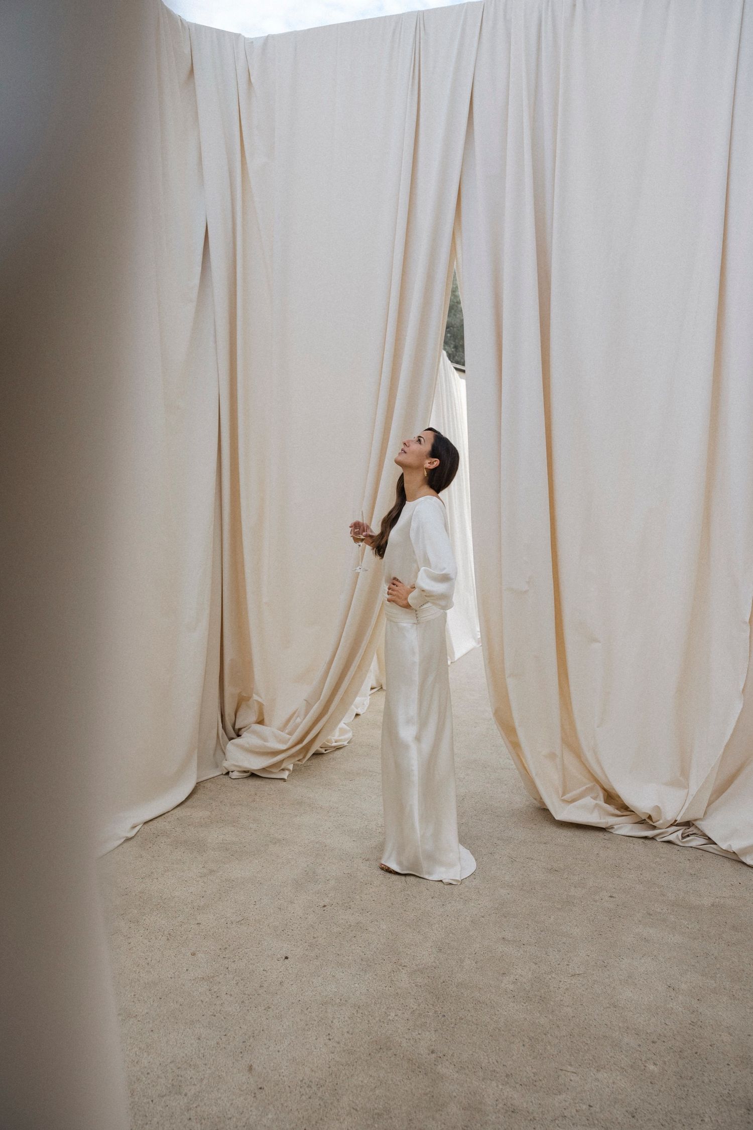 Artistic black and white photo series showing a person emerging through white curtains in a minimalist setting.