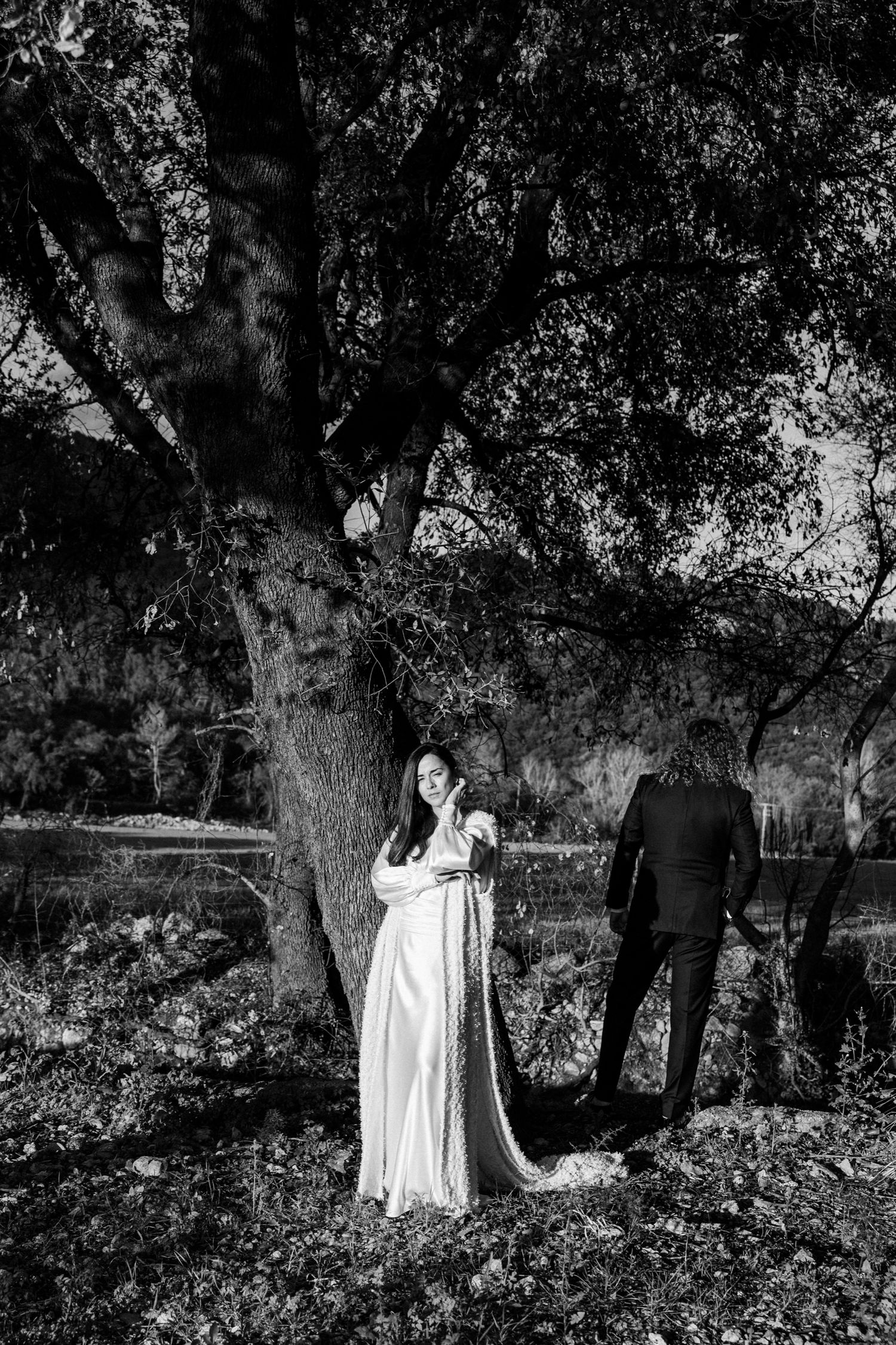 Black and white photograph of figures in a dreamy forest setting with dramatic lighting.