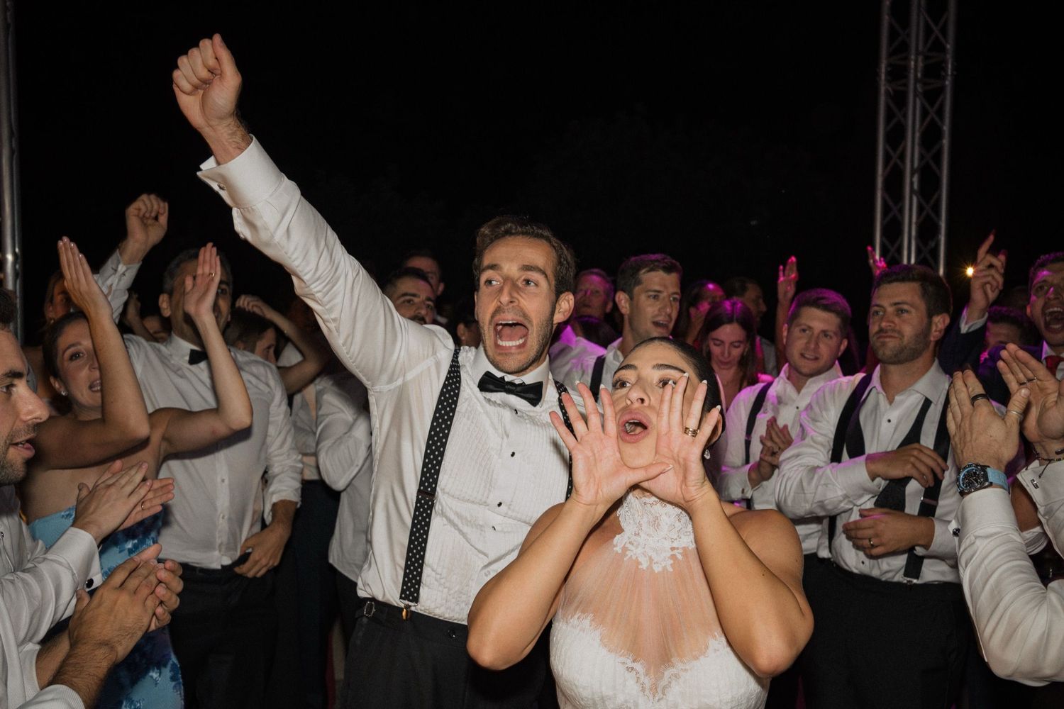 Wedding reception party guests dancing and celebrating energetically on the dance floor during a festive moment.