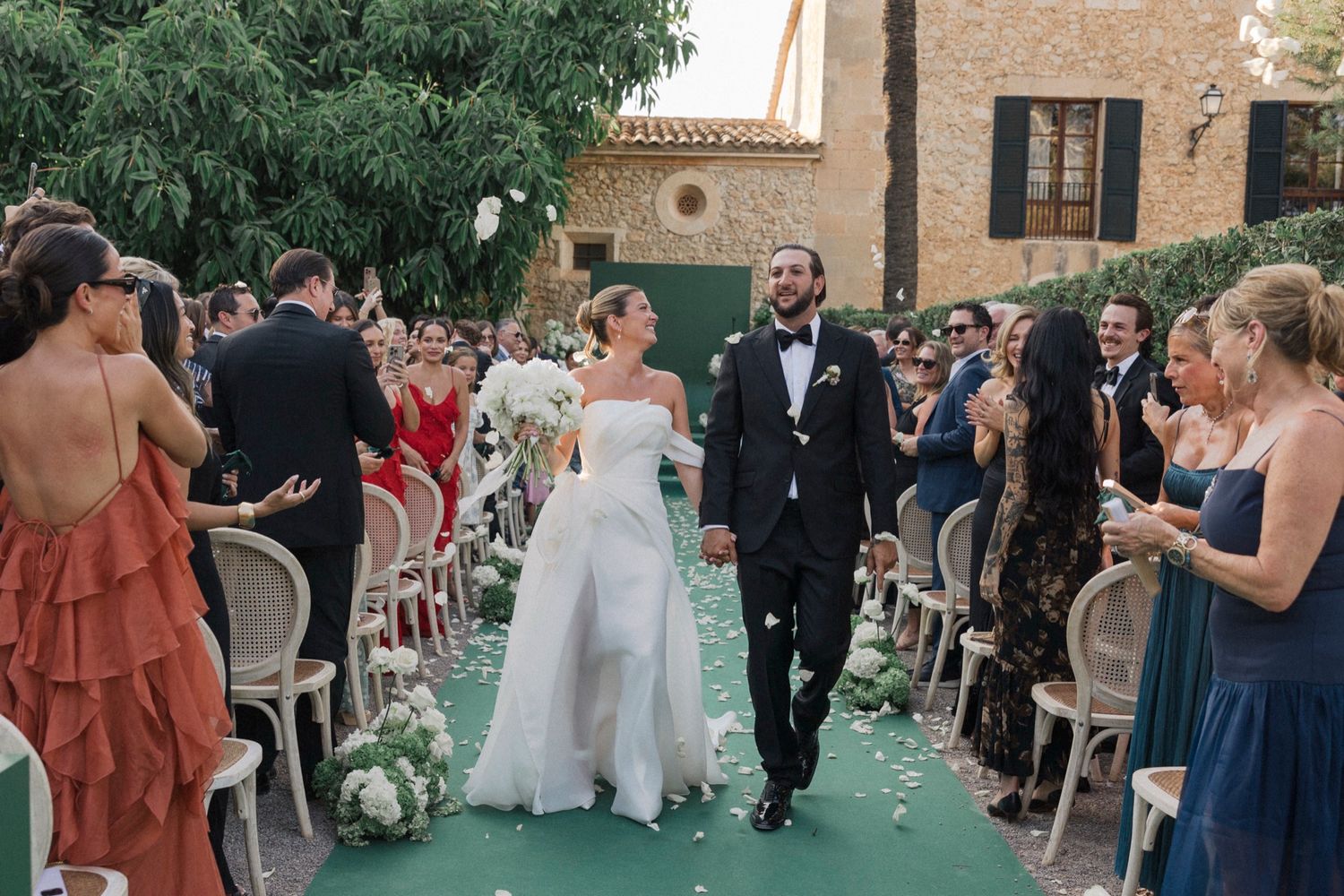 Wedding celebration with guests in formal attire at outdoor Mediterranean venue.