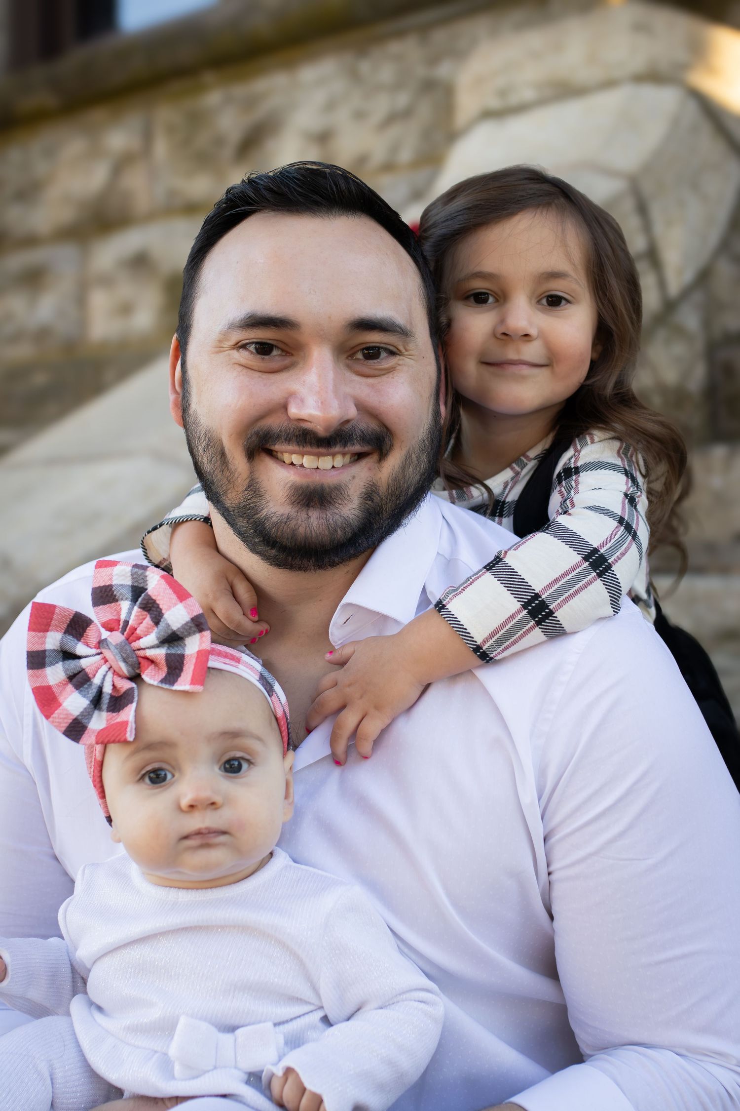 Sweet portrait of parent with two children on stone steps outdoors.