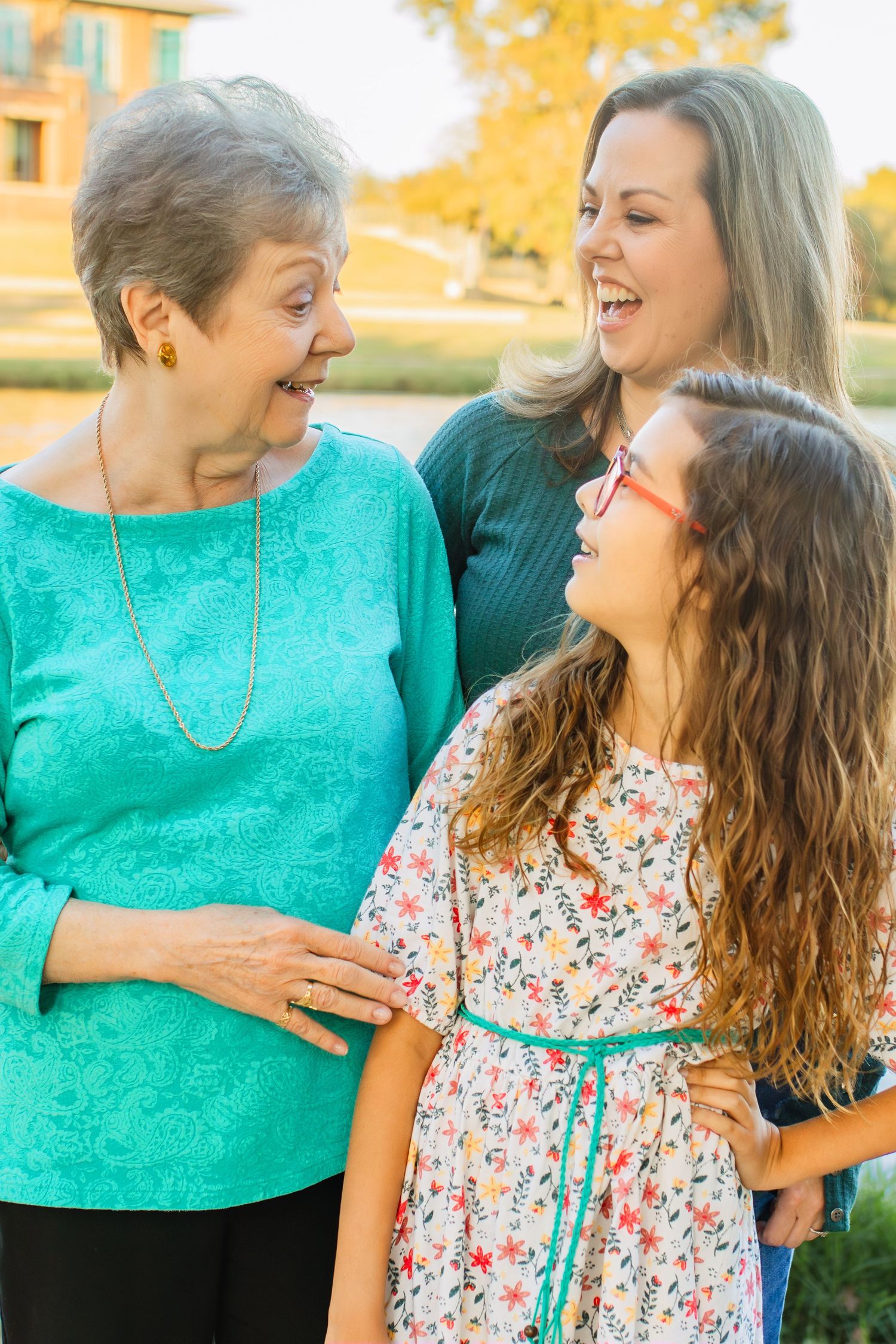 Three generations share joyful laughter together outdoors on a sunny autumn day.