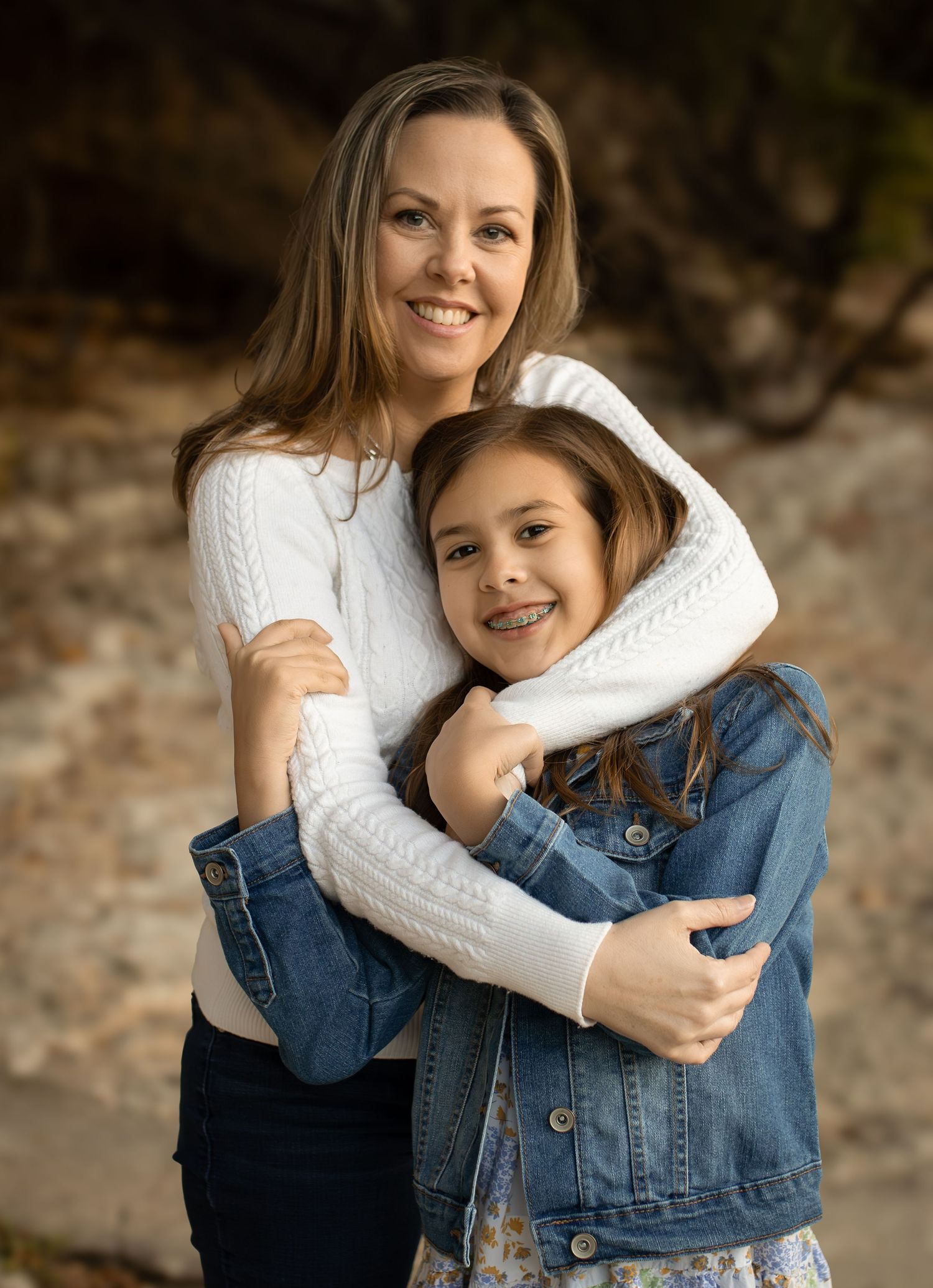 Warm portrait of two people embracing and smiling in casual attire.