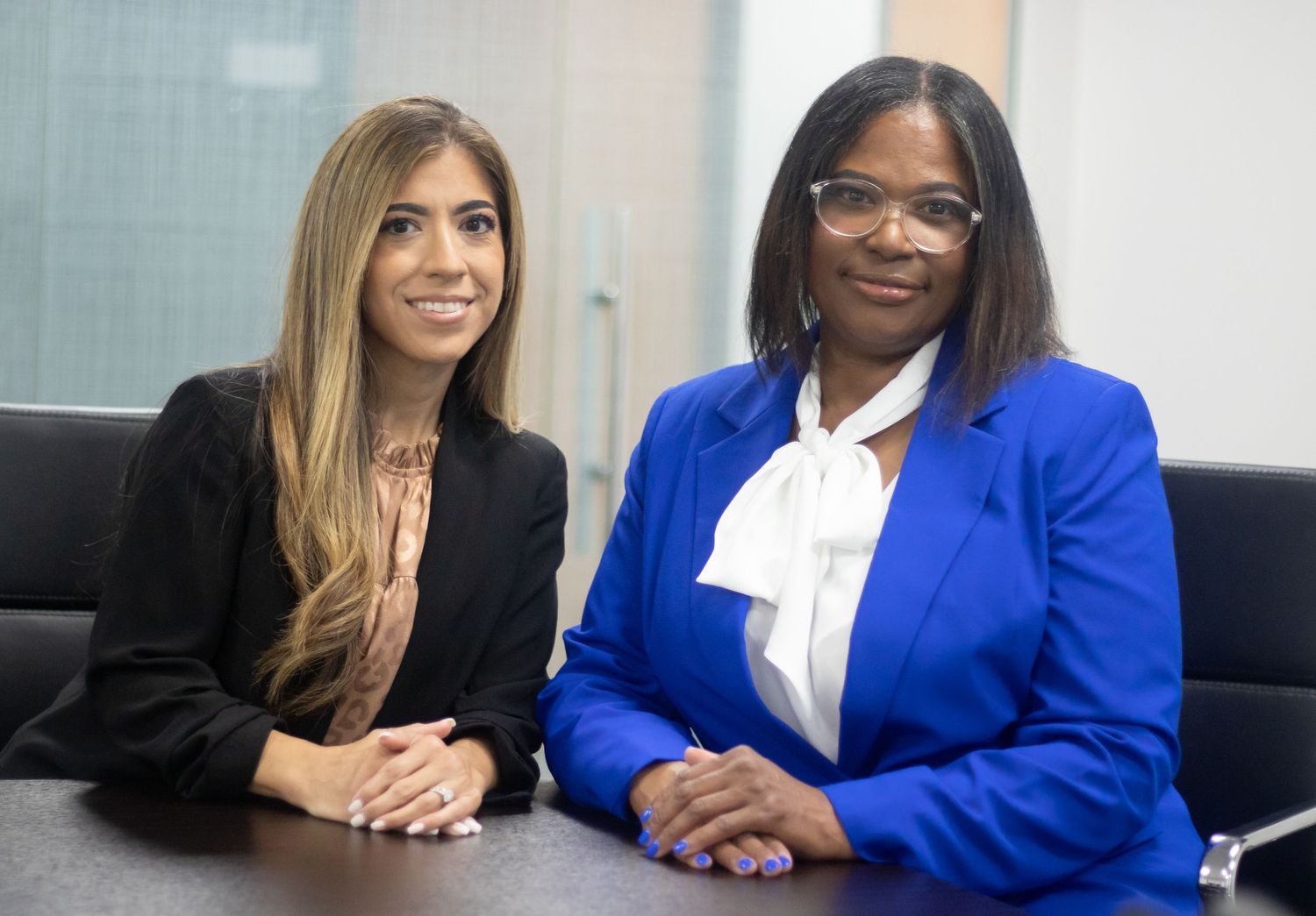 Two professionals in business attire sit together during a meeting at a modern office.