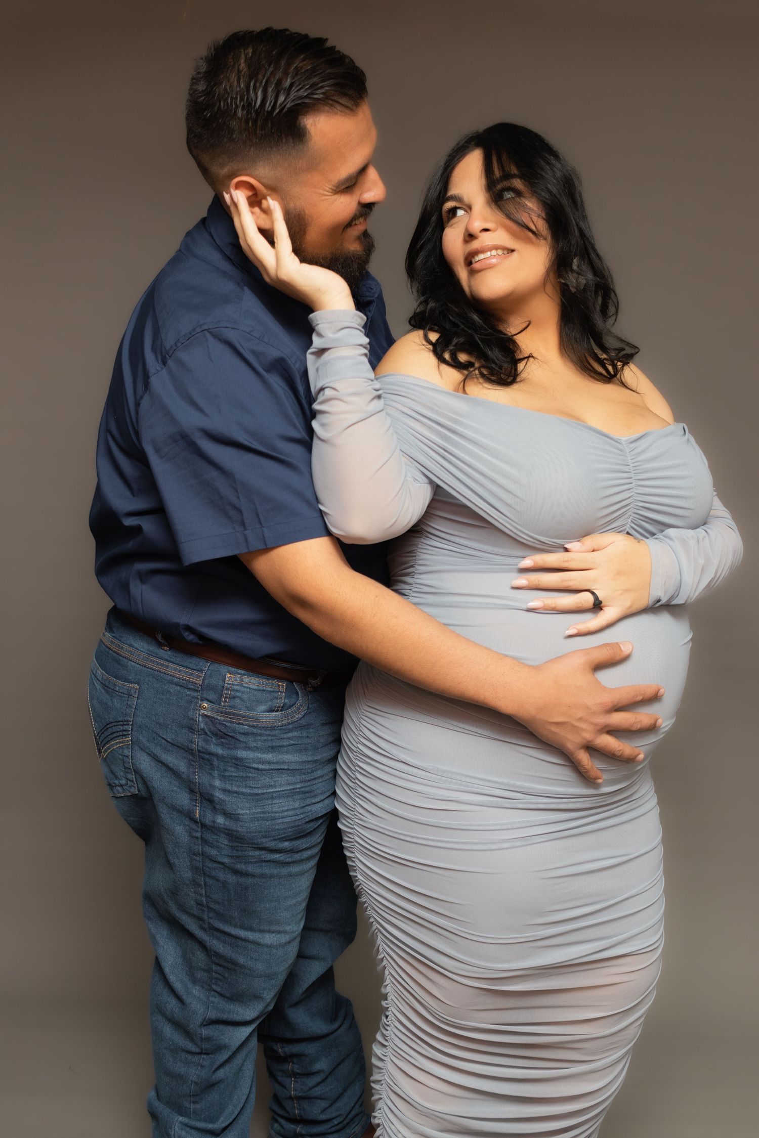 A loving, expectant couple poses in a Fort Worth studio for their couples maternity portrait session.