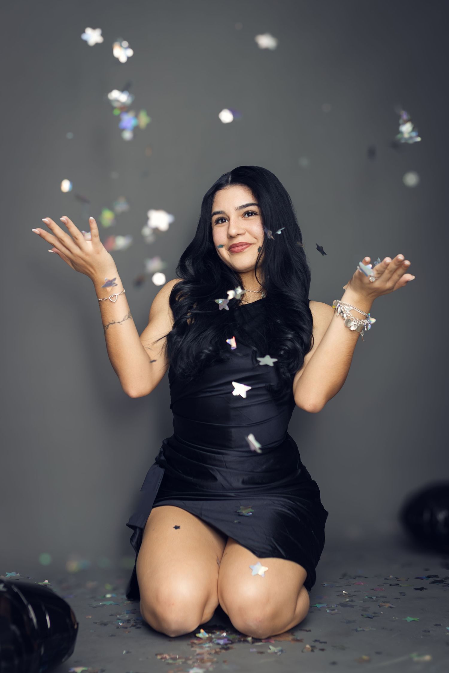 A celebratory portrait with a woman in black throwing confetti in the air.