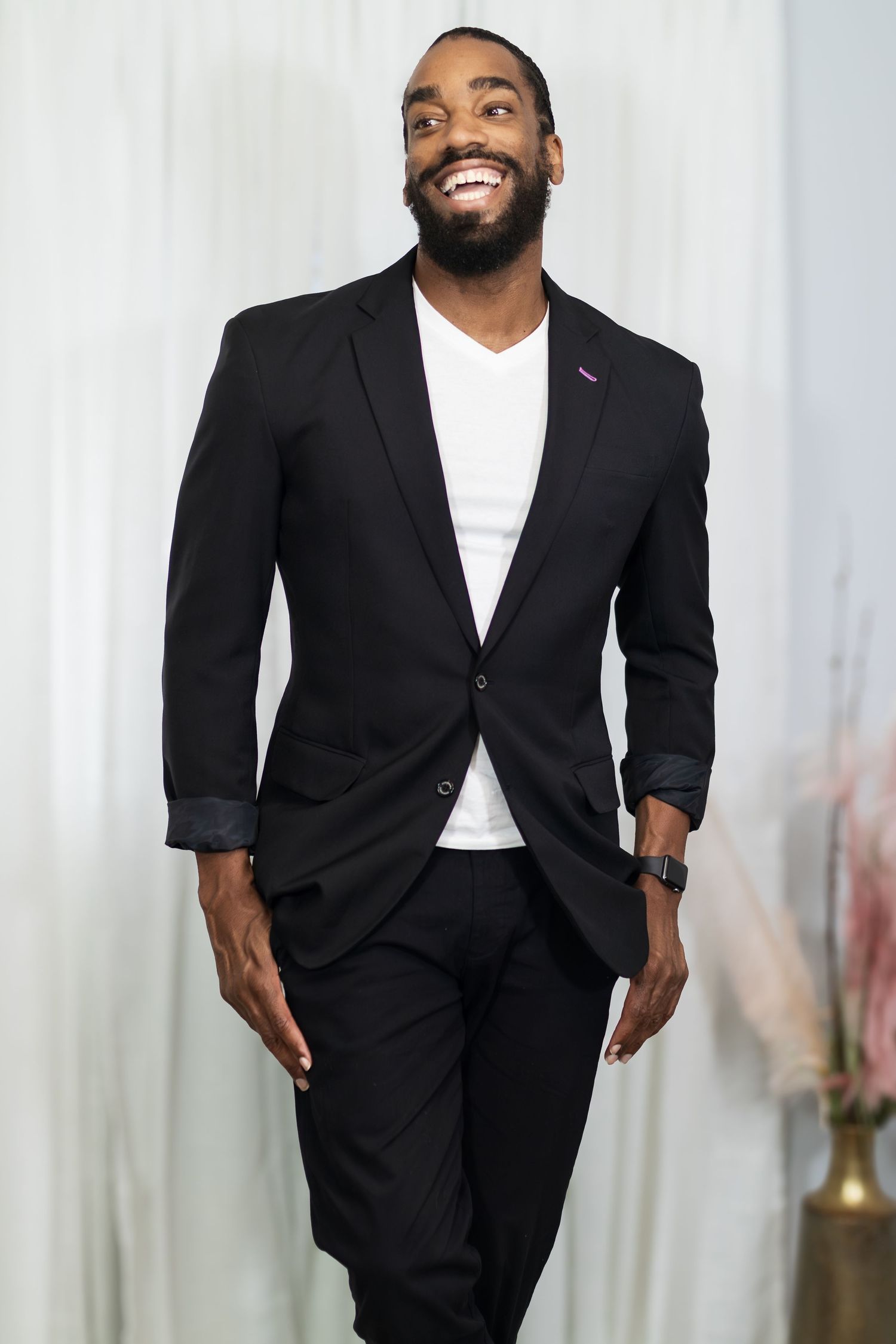 Professional headshot of man in black suit jacket and white shirt against light background.