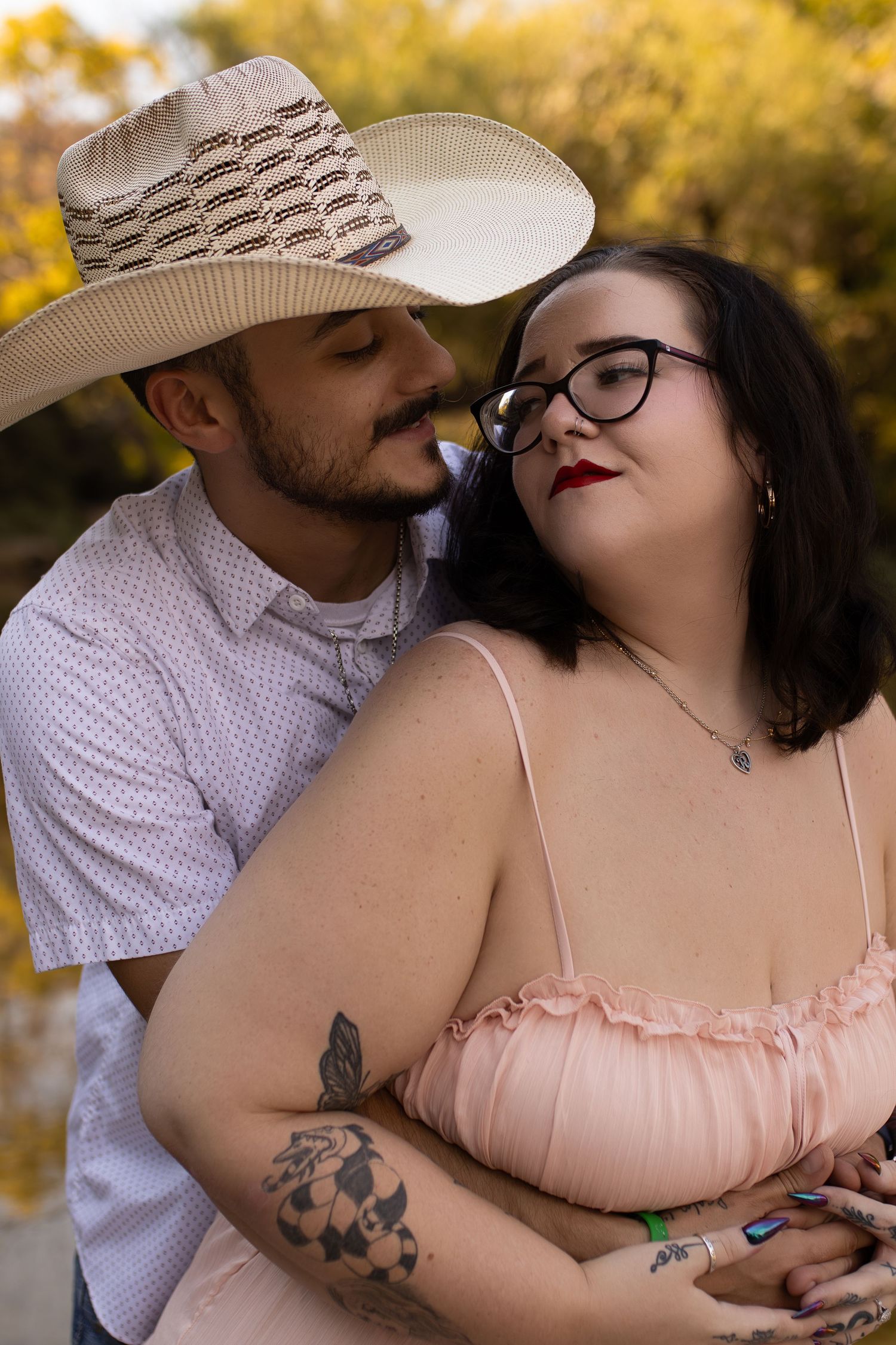 An intimate moment captured between a couple as they embrace under golden autumn foliage.