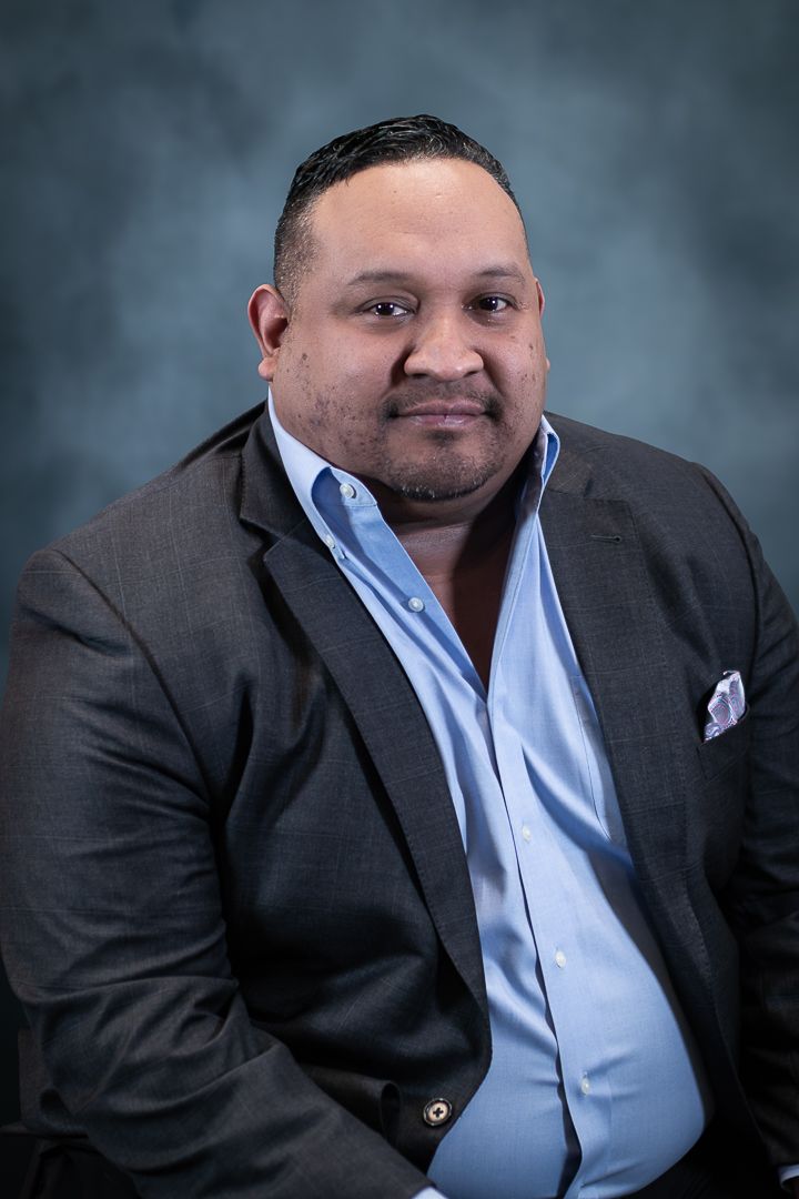 Professional headshot of businessman in dark suit and light blue shirt.
