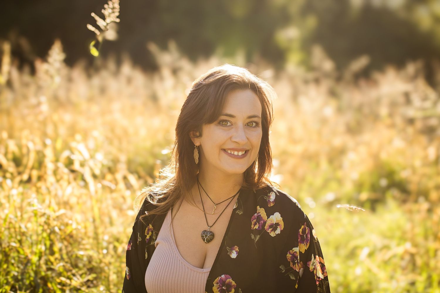 Portrait in a golden field at sunset wearing a floral cardigan and necklace.