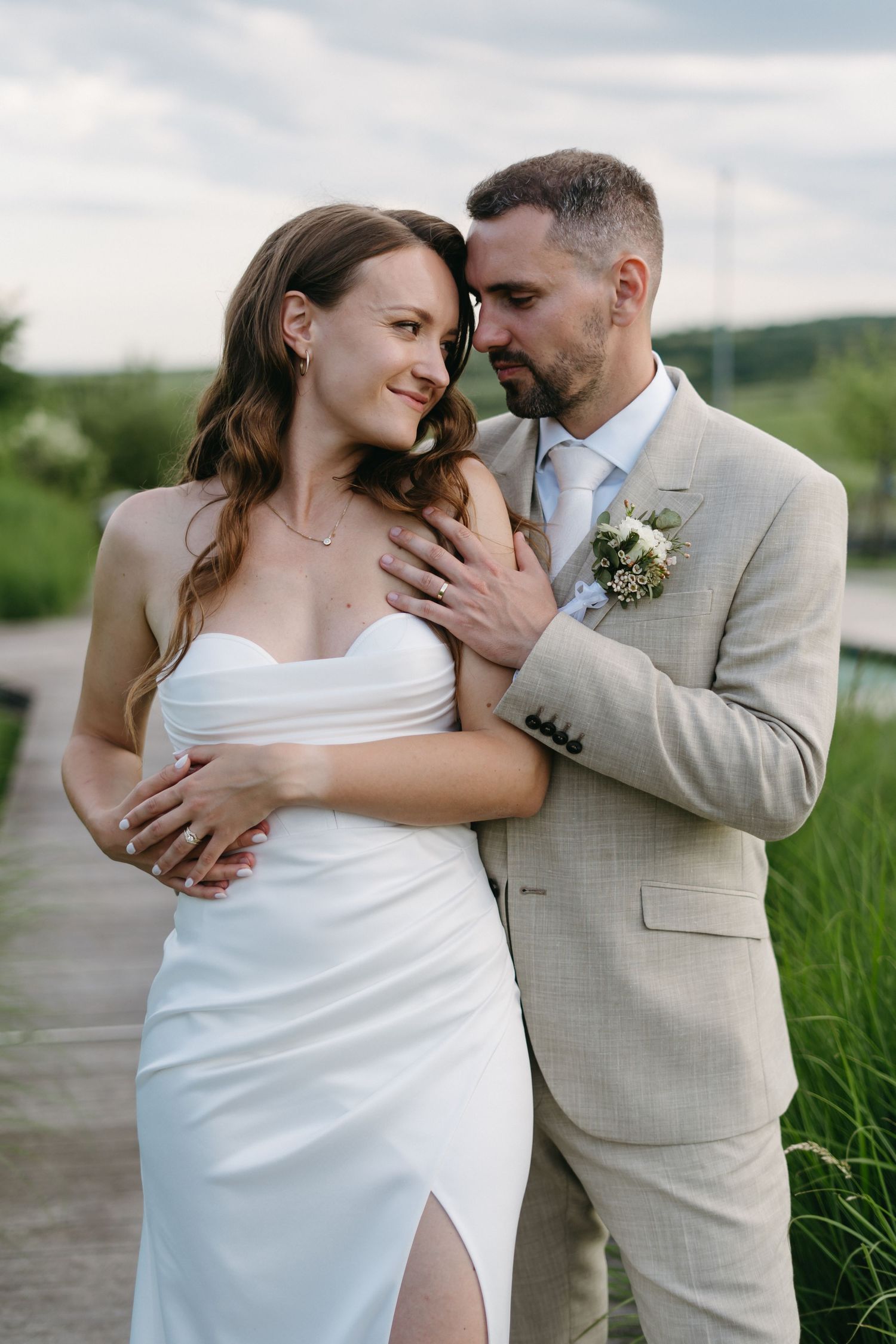 Intimate moment between bride and groom outdoors with scenic countryside backdrop.