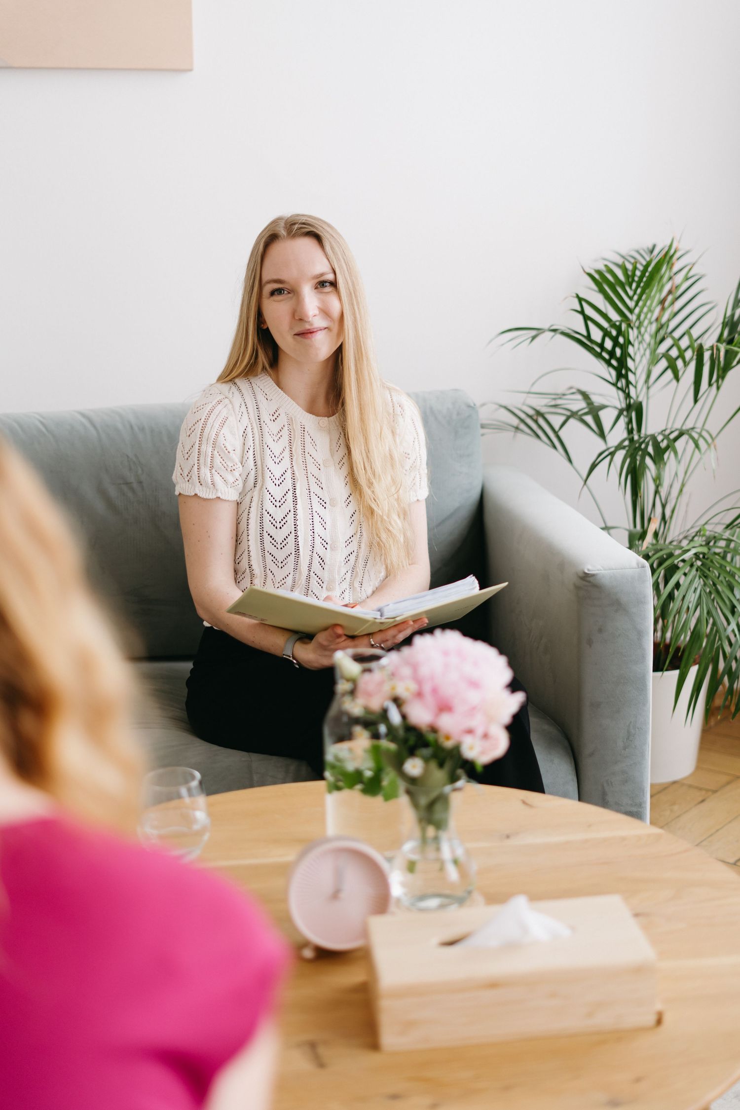 A consulting meeting at home with a decorative plant and pink flowers on a wooden coffee table.