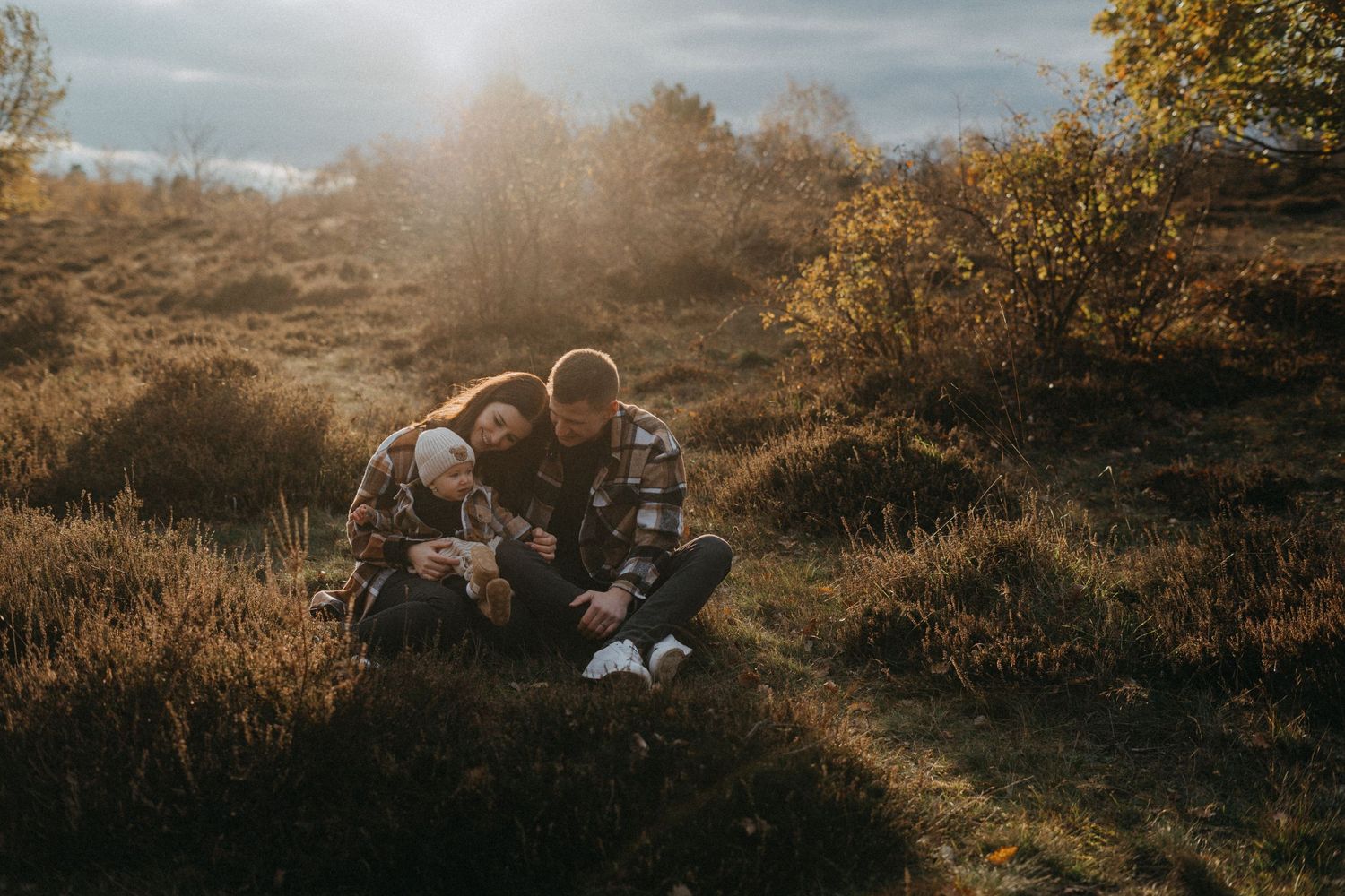 Family enjoying sunset moment together in golden autumn field landscape.