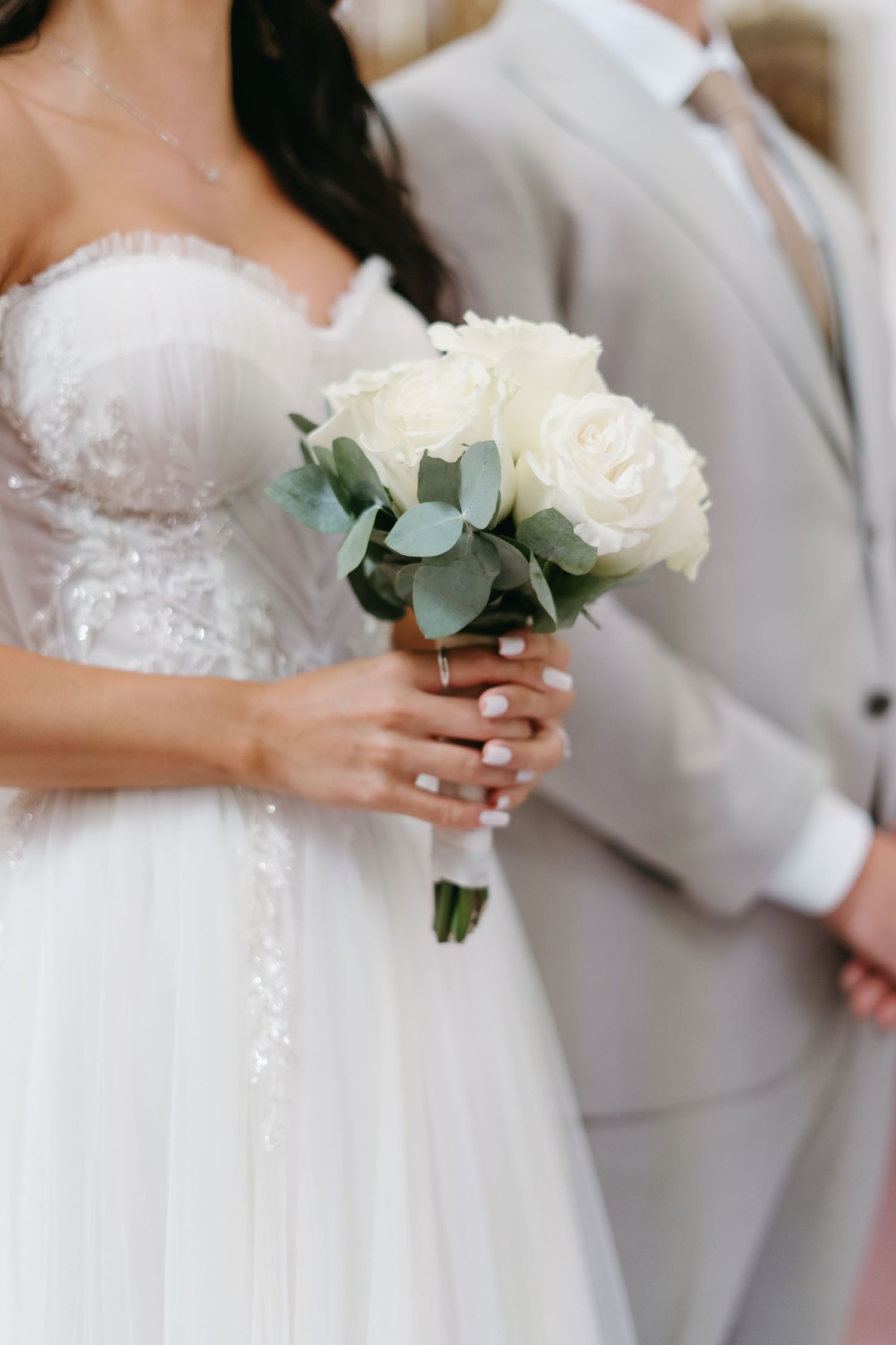 Classic white rose and eucalyptus bridal bouquet with lace wedding dress detail.