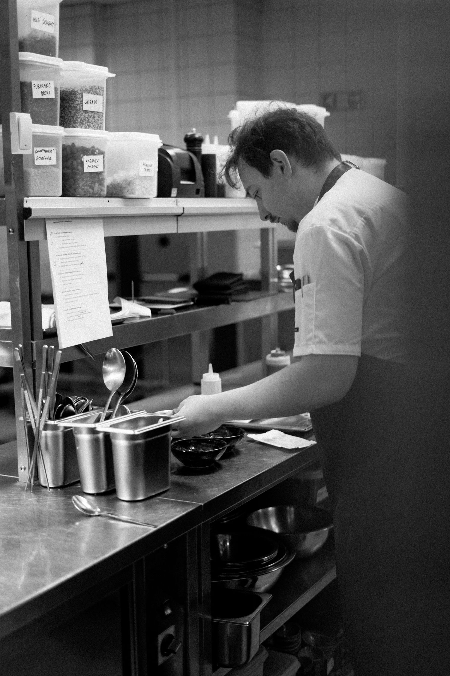 Black and white view of a commercial kitchen counter with stainless steel equipment in low light conditions.