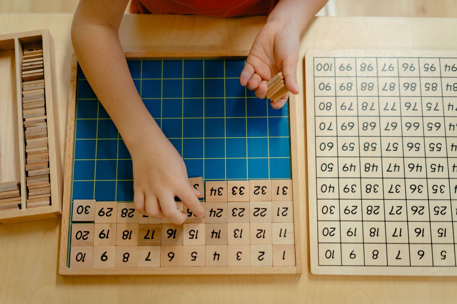 Students practice math using wooden number squares and manipulatives in a classroom learning activity.