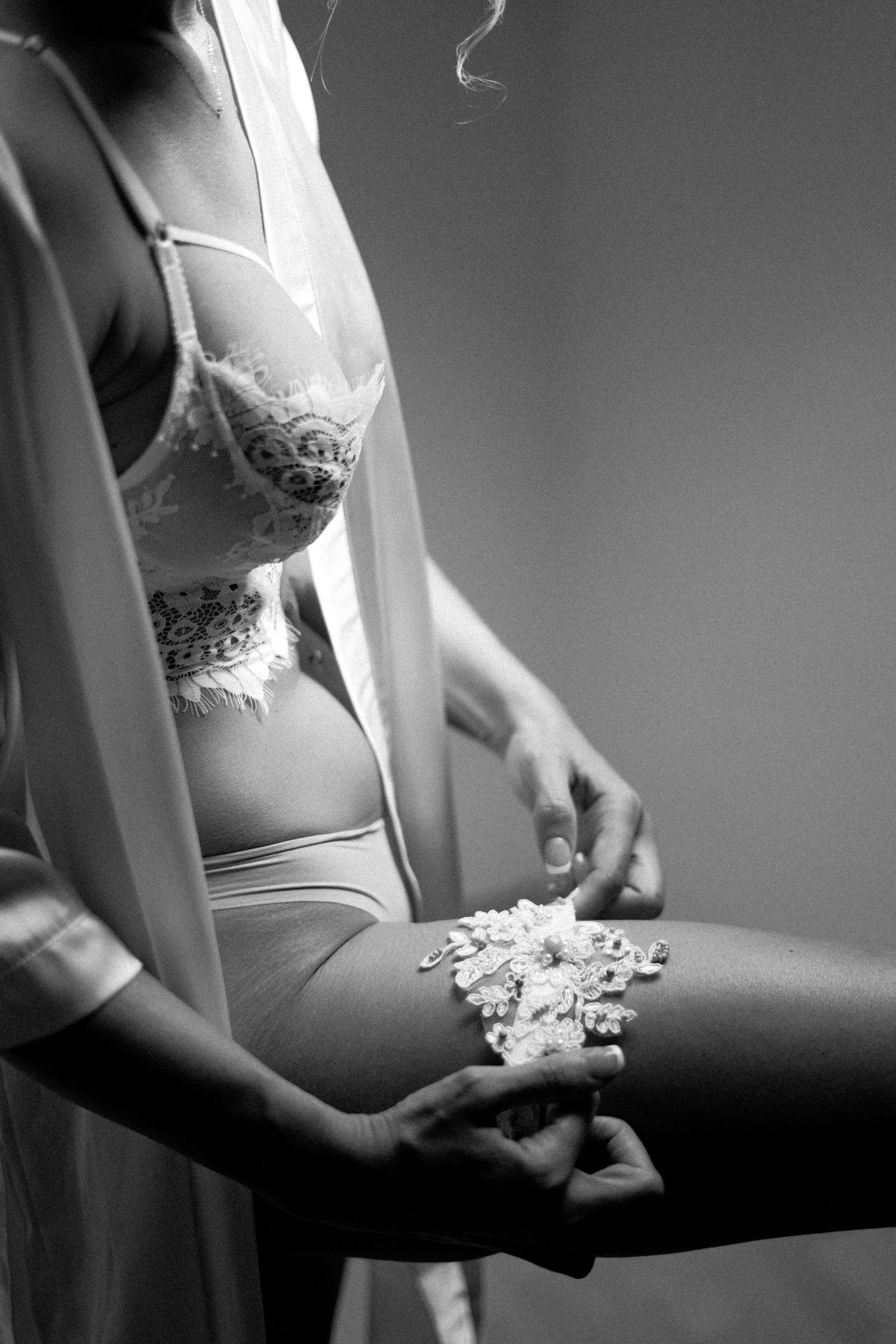 Black and white intimate boudoir photo showing lingerie and a lace robe with delicate details.