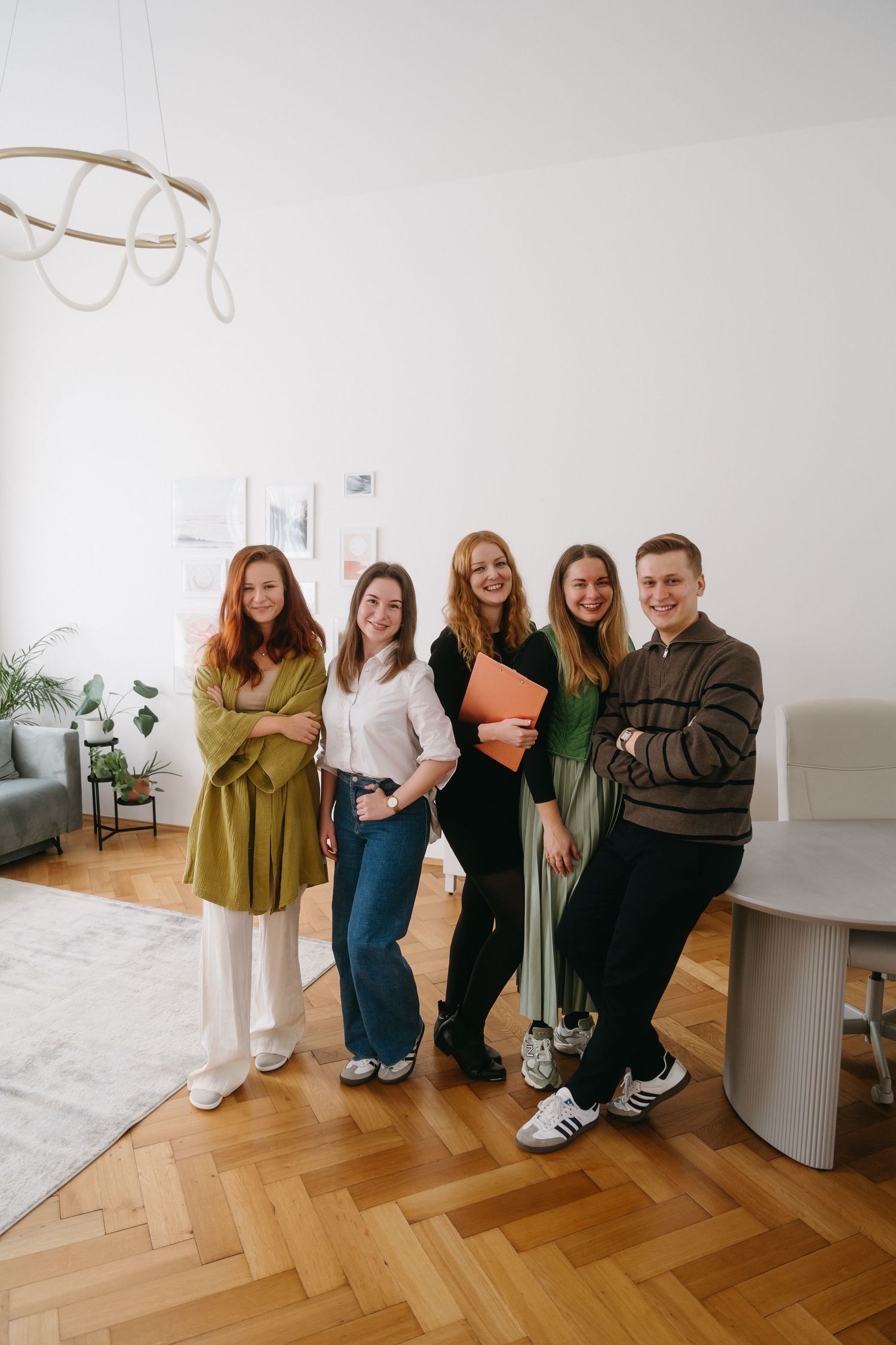 A team of professionals standing together in a bright modern office space with herringbone wood flooring.