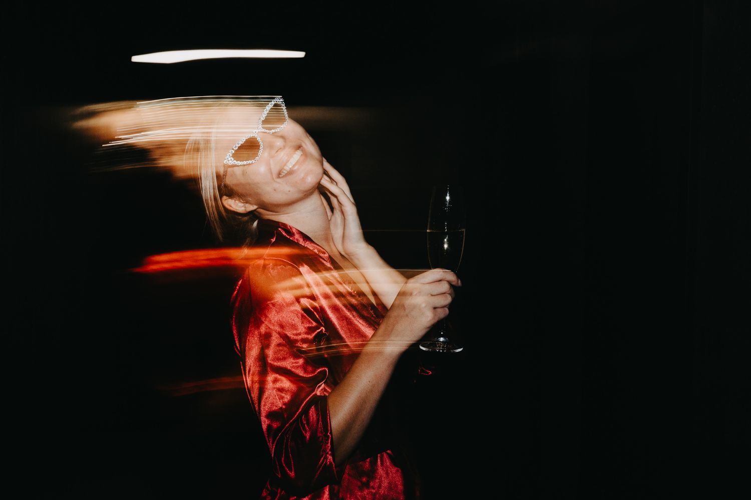 Creative motion blur portrait of woman in red dress holding wine glass.