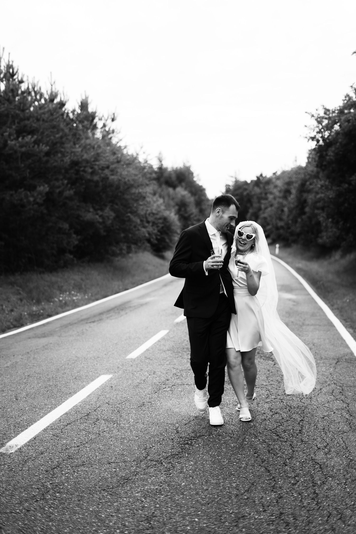 Black and white photo of a couple playfully posing with dance moves on an empty road.