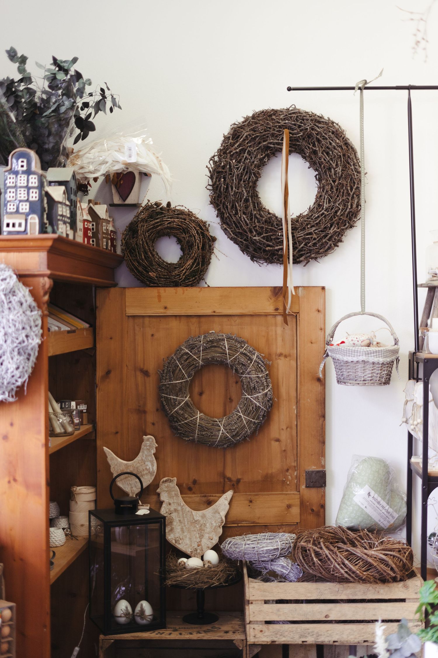 Rustic country decor display with twig wreaths and wooden chicken ornaments in a cozy corner setting.
