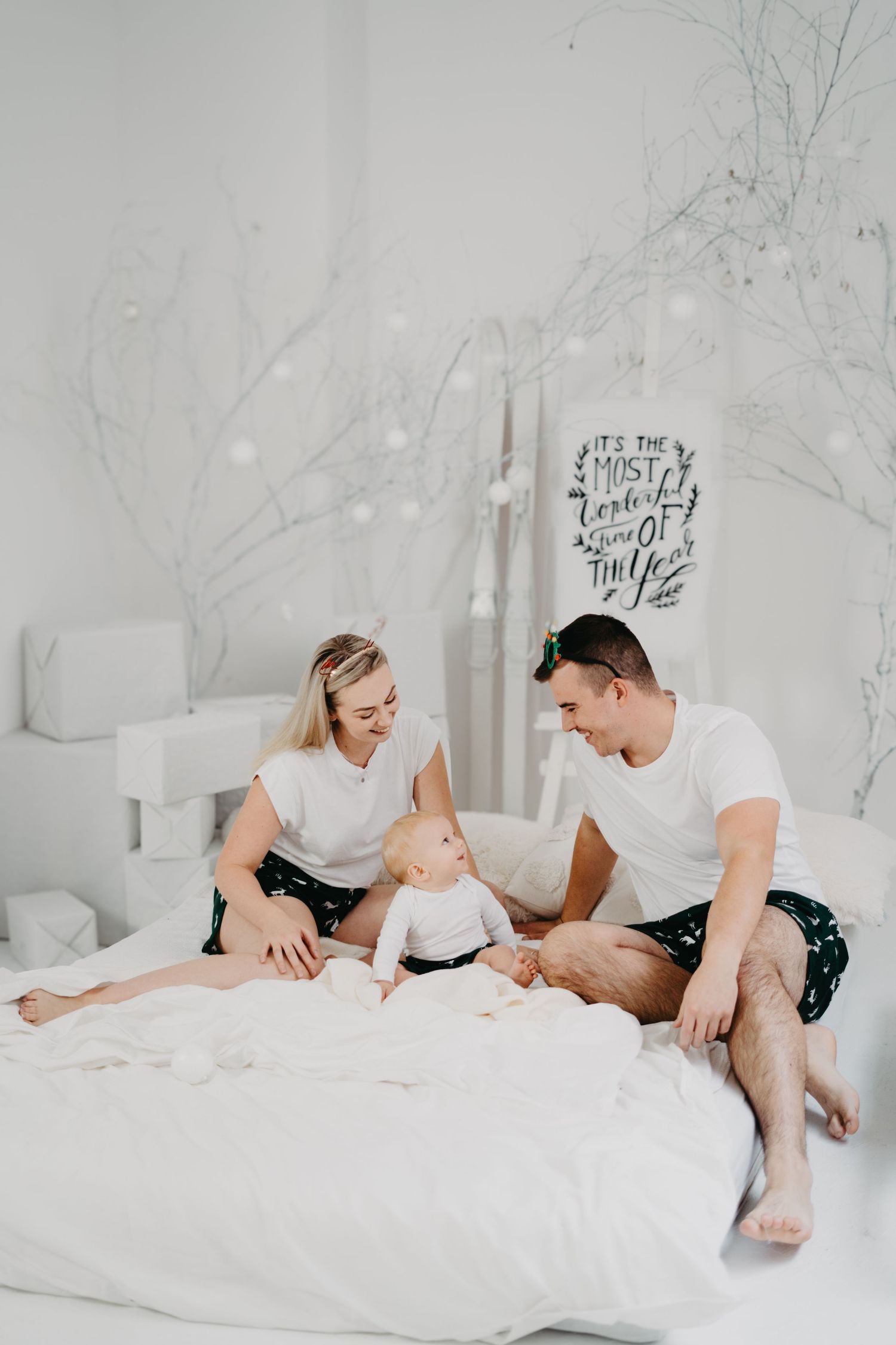 Family relaxing together in classic white couch studio photoshoot with minimalist aesthetic.