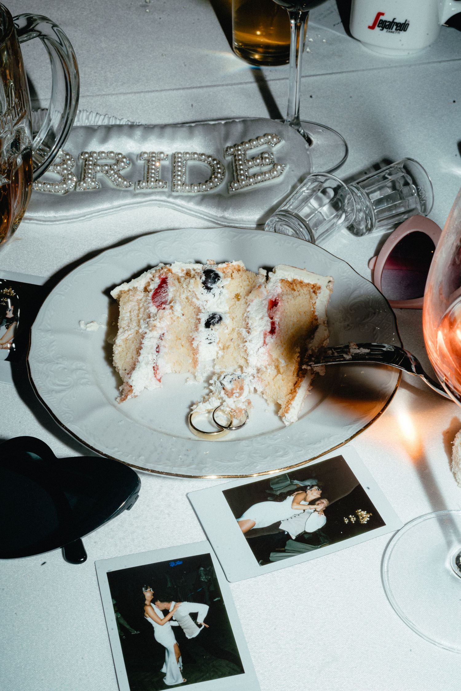 Partially eaten slices of white wedding cake on plates with candlelight illuminating the scene.