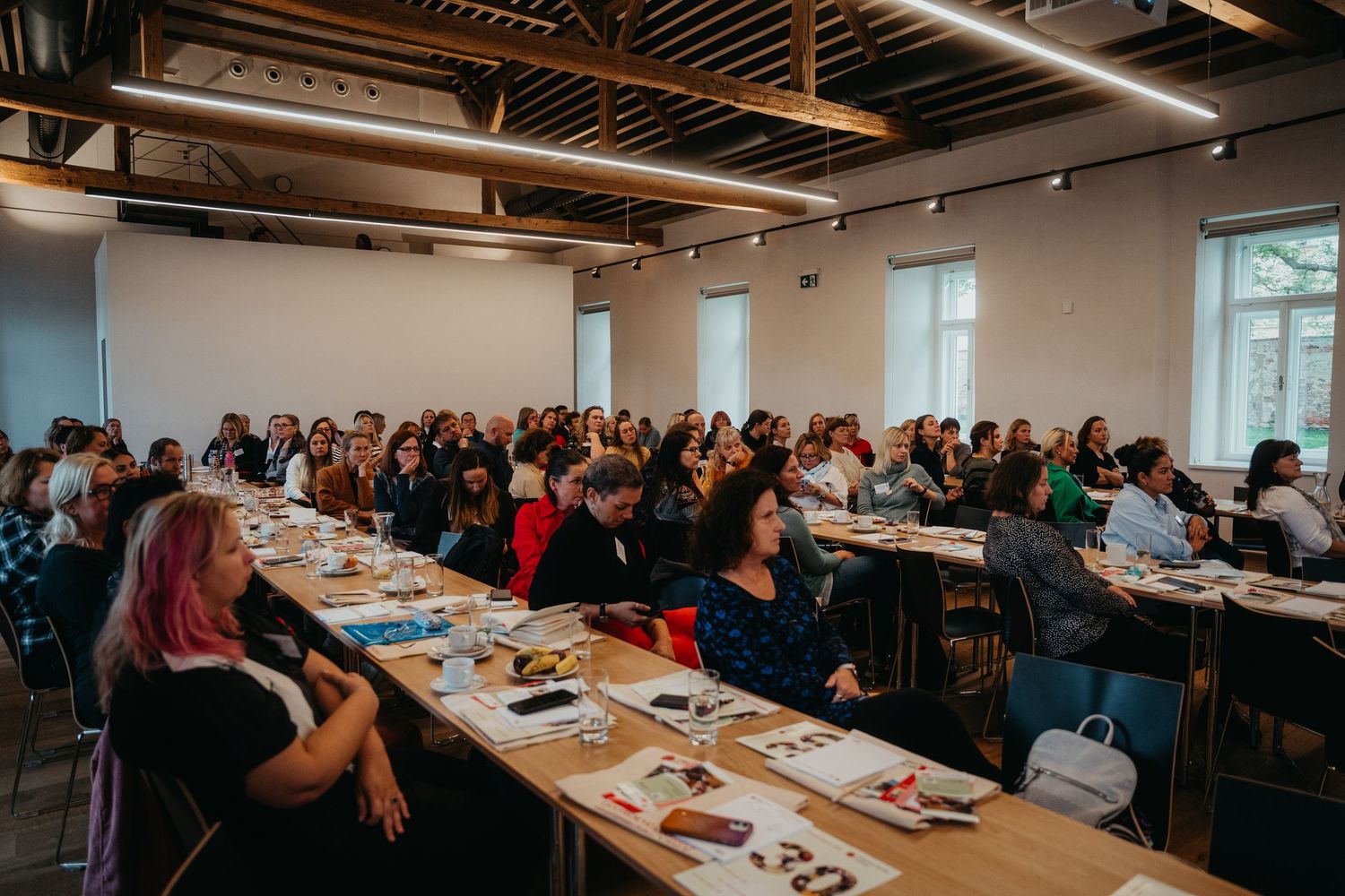 Large group of professionals attending a workshop or training session in a modern conference room setting.