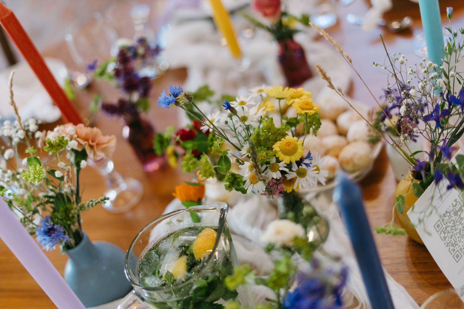 A collection of colorful floral centerpieces with wildflowers and pastel blooms arranged in vases for an event.