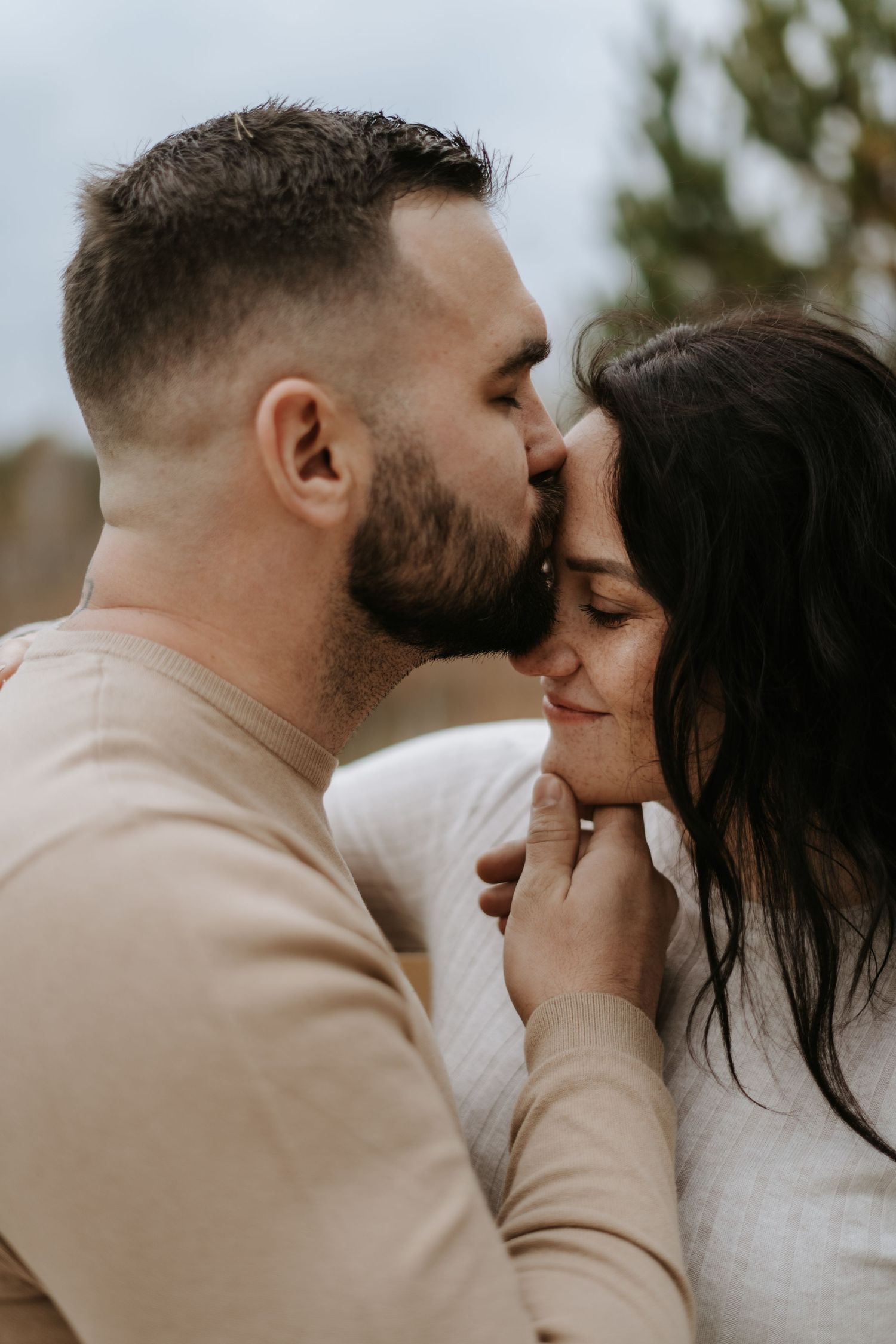Romantic couple shares tender moments during their outdoor maternity photoshoot.