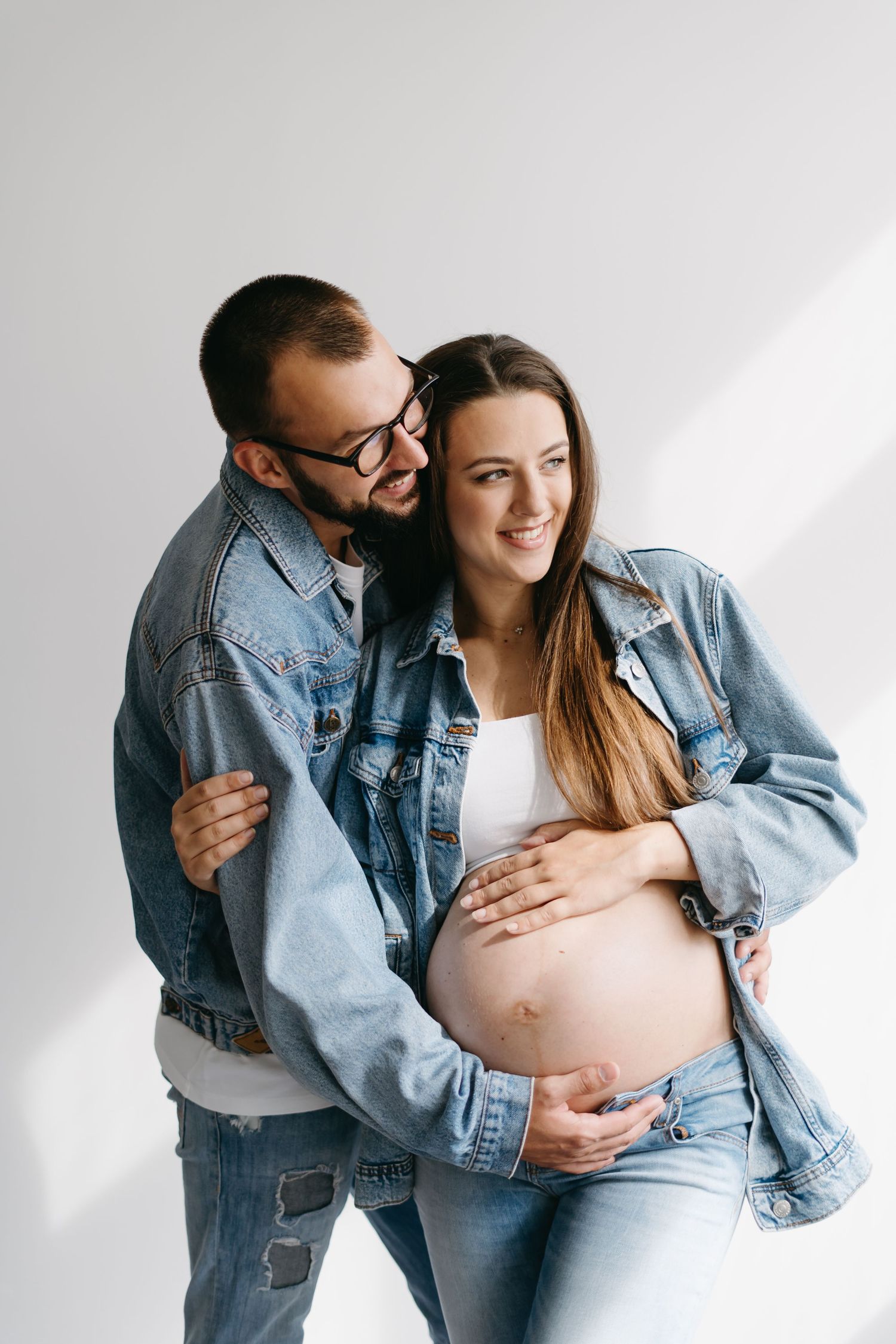 Casual maternity session features couple in denim sharing joyful moments.