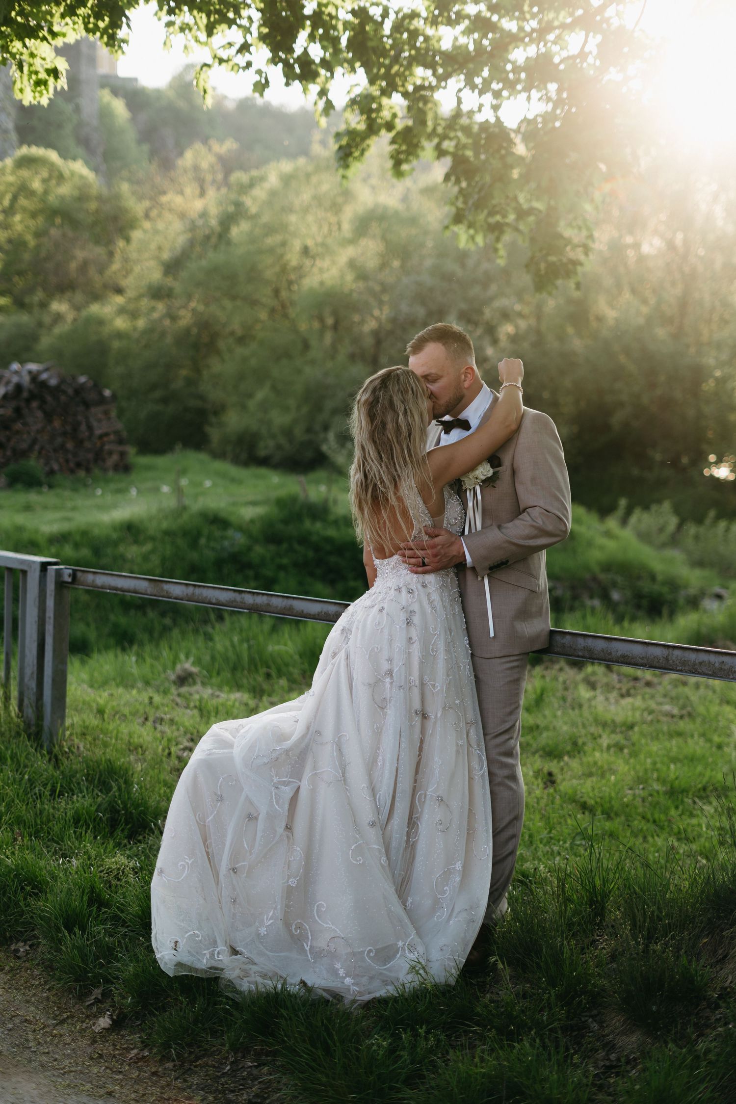 Romantic wedding couple embraces in dreamy sunlit garden setting during golden hour photography session.