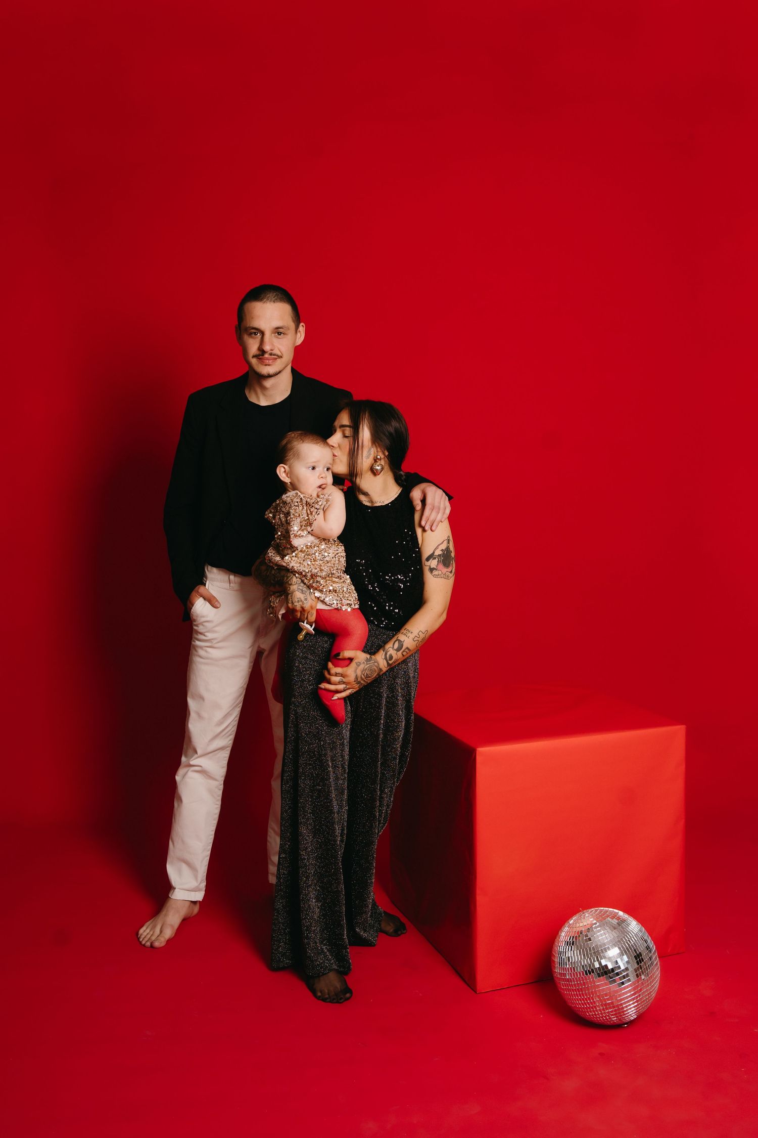 A series of four red studio portraits showing a parent and child posing together with a disco ball on the floor.