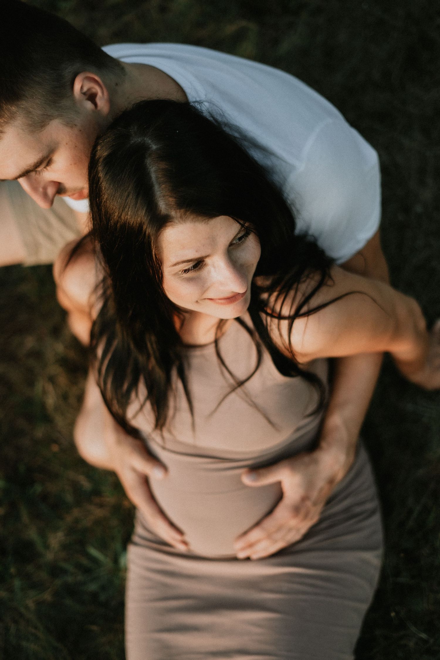 Intimate maternity portrait captured in warm evening light outdoors.