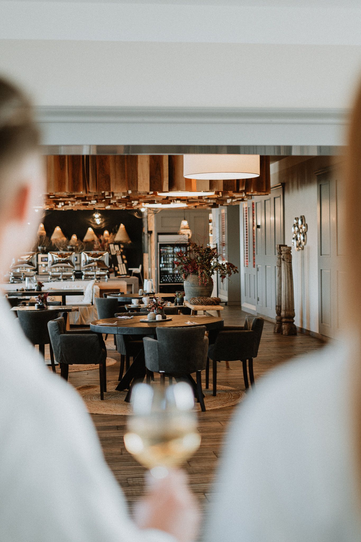 Modern restaurant interior with wooden floors and elegant dining tables arranged in a spacious open layout.