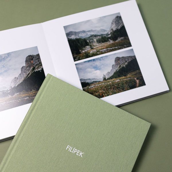 Minimalist sage green folders and photographs arranged artistically on matching green background surface.