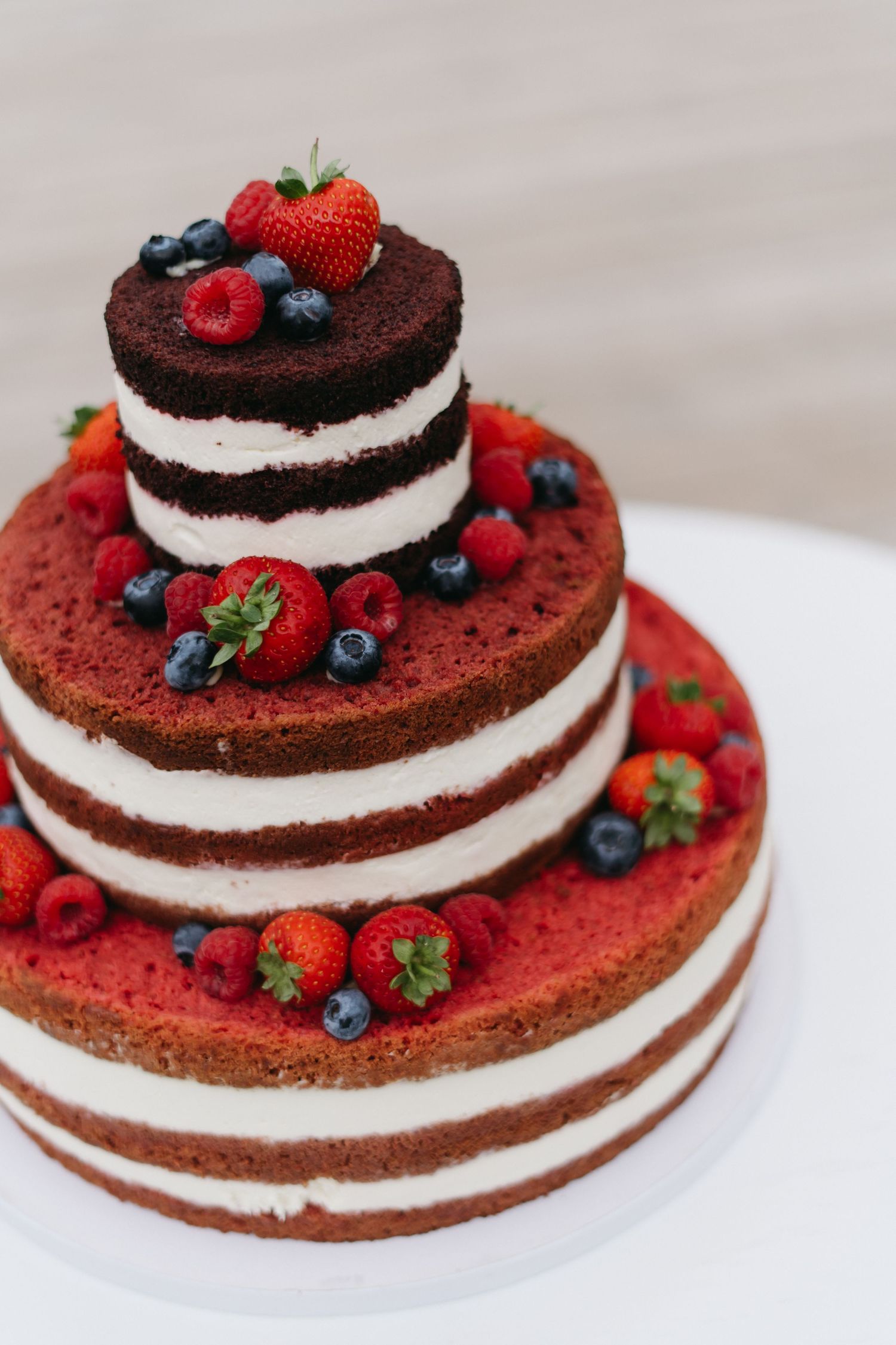 Red velvet cake with cream filling and fresh berries arranged in different views showing inner layers and toppings.