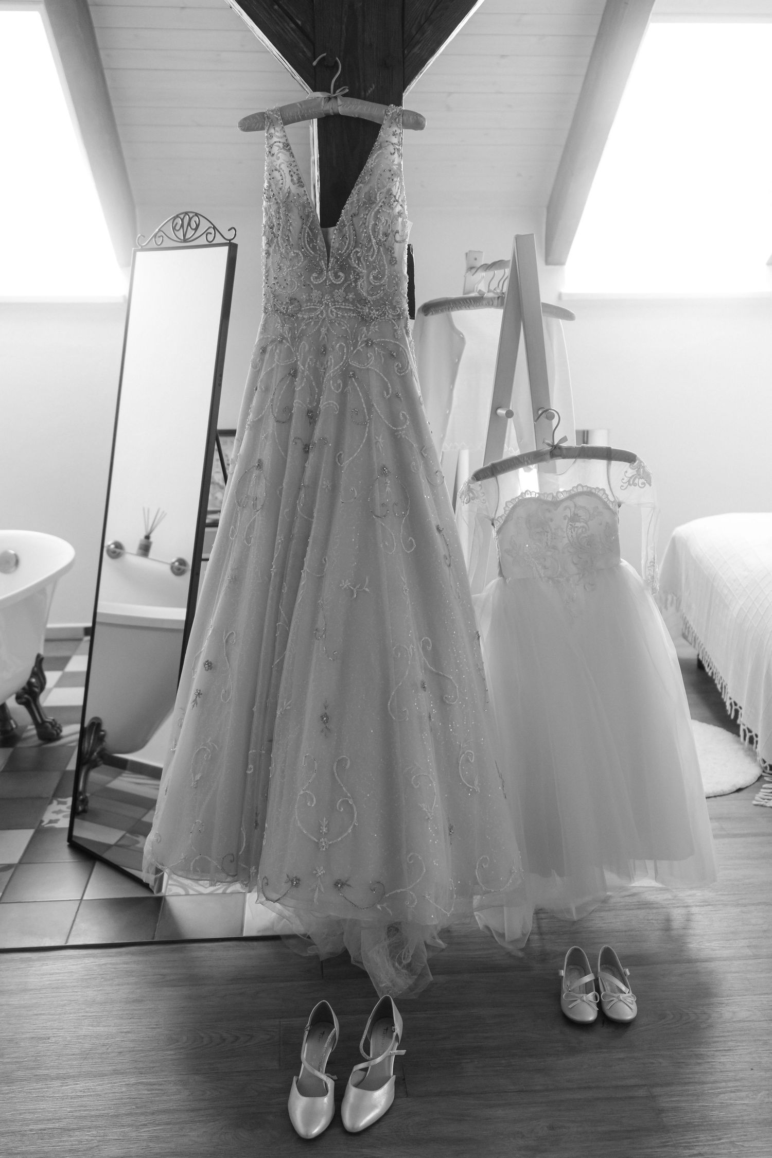 Elegant white wedding dresses displayed with shoes in bridal preparation room.