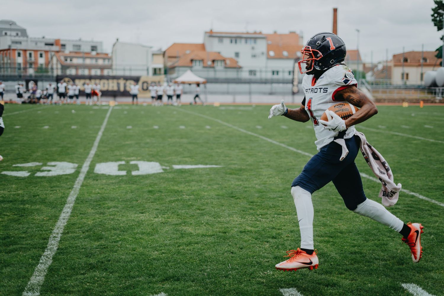 Athletes perform dynamic stretching exercises on a football field during warm-up drills.
