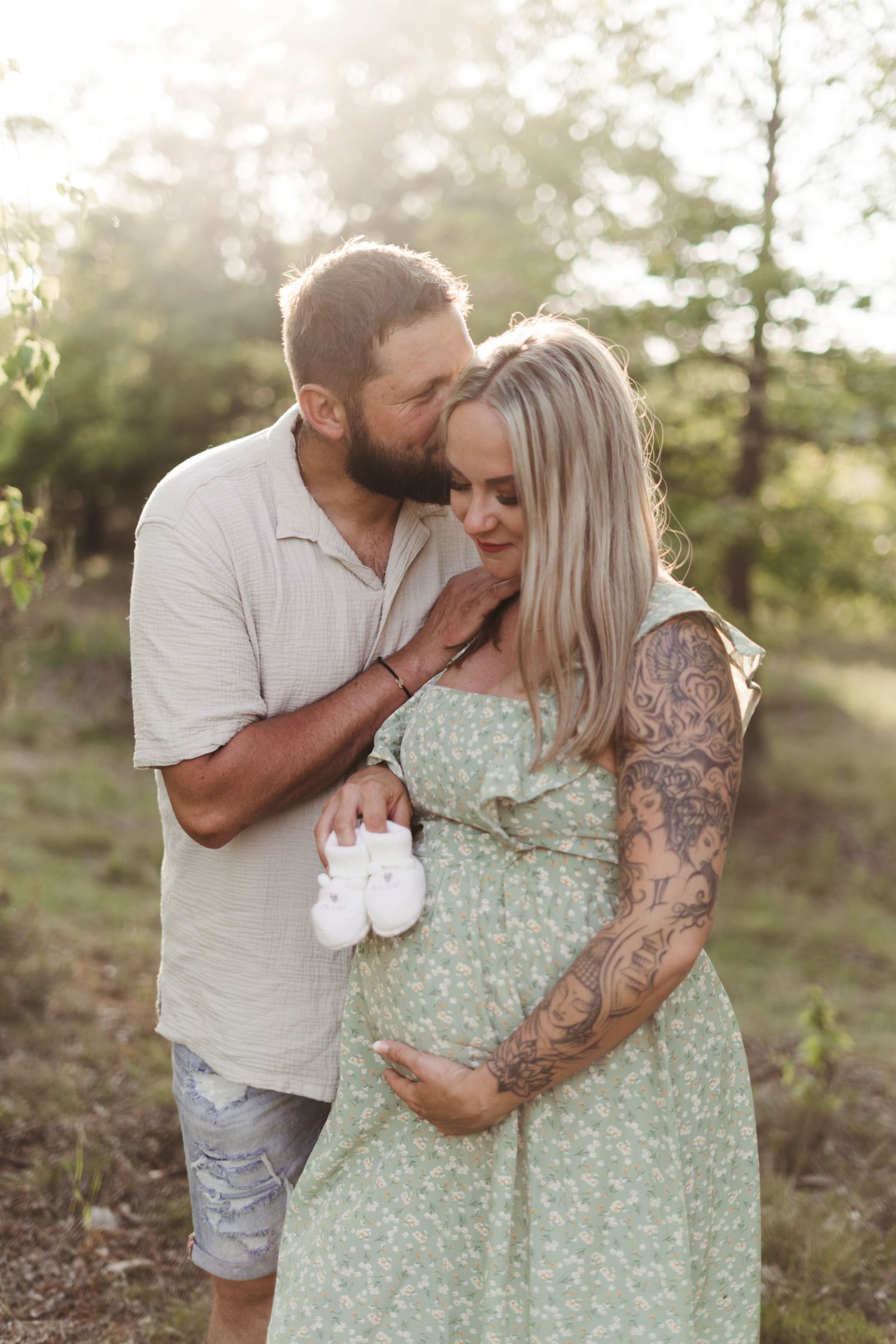 Outdoor maternity session with couple in soft mint dress and white shirt amid natural scenery.