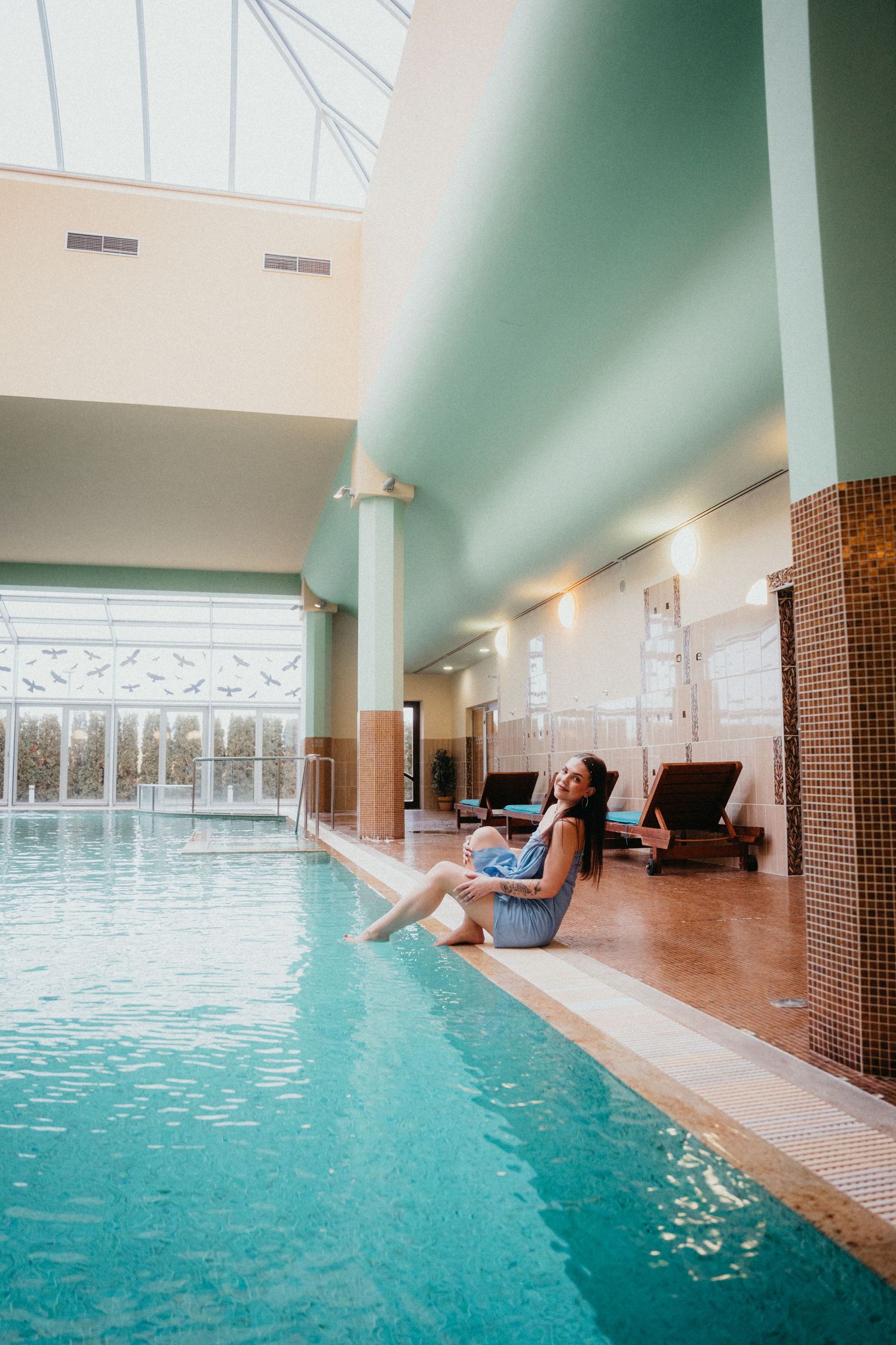 Luxurious indoor pool at a spa resort with turquoise water, loungers, and natural light streaming through large windows.