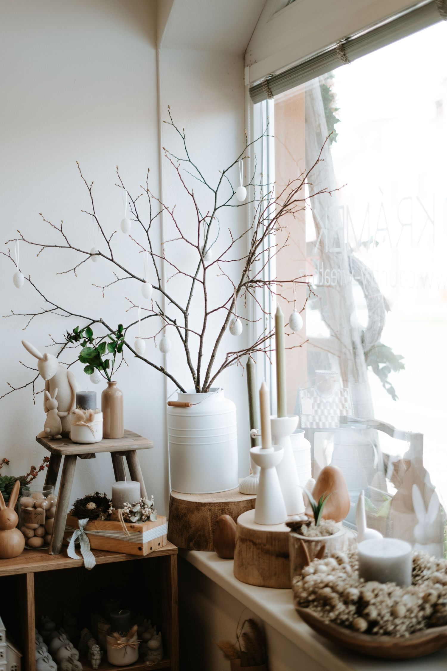 Minimalist winter decor with bare branches in white vases arranged on wooden windowsill with natural light.