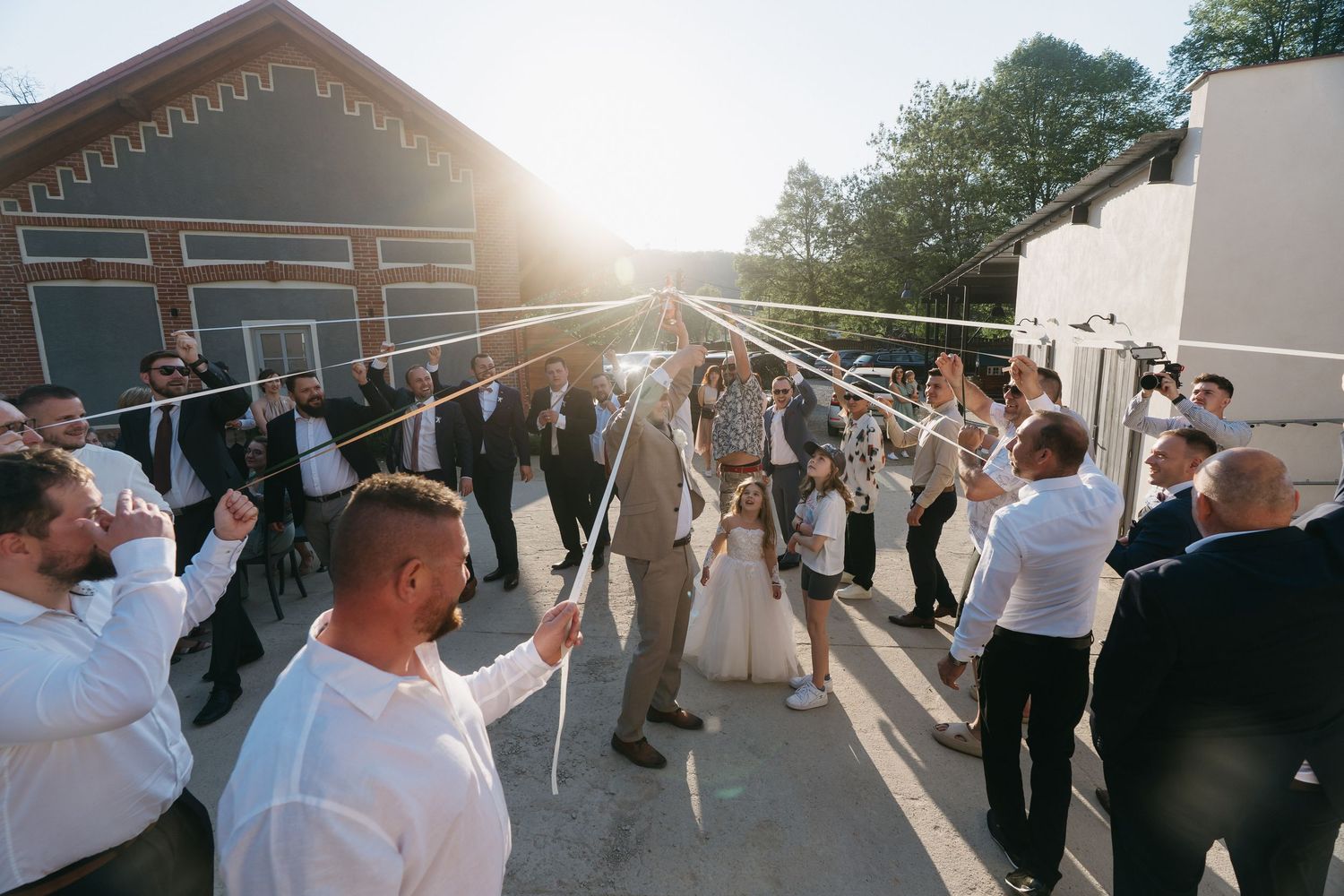 Wedding guests form a tunnel of raised sparklers as a couple exits through their sparkler send-off at sunset.