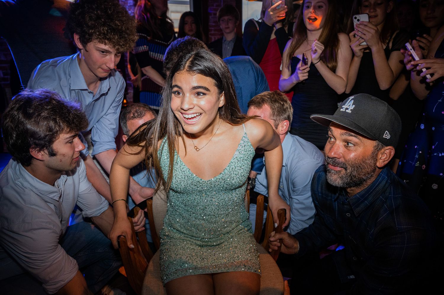 People enjoying themselves on a crowded dance floor in a nightclub with blue lighting.
