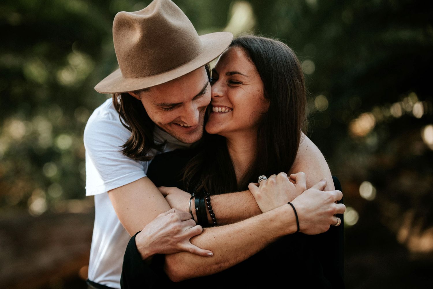 Intimate couple embraces outdoors as they share a loving moment in nature with soft bokeh lighting.