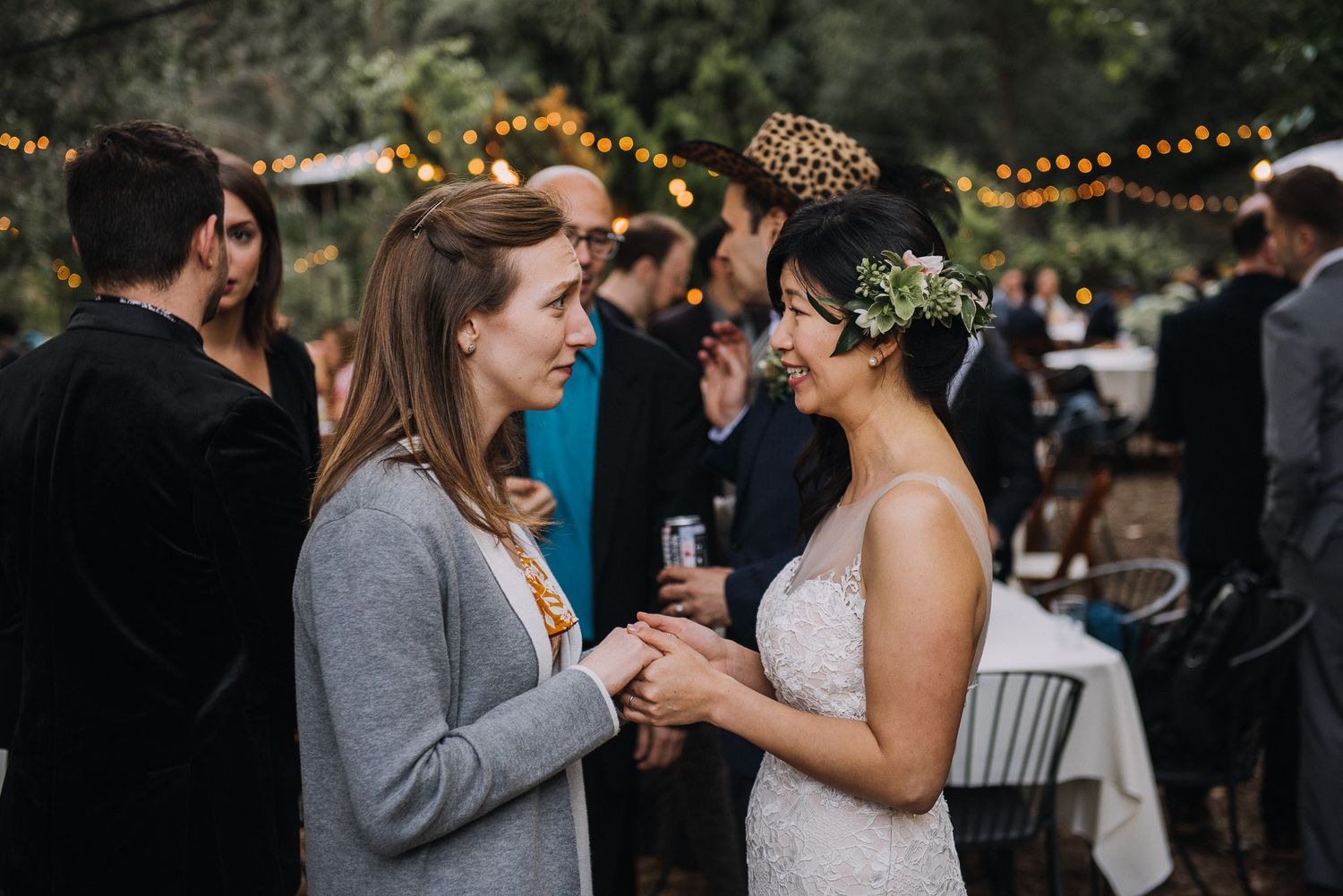 A couple shares an intimate moment during their outdoor wedding reception with string lights glowing in the background.