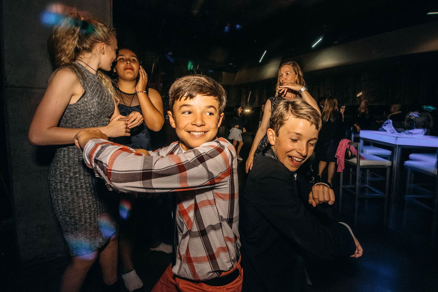 People dancing and having fun in a dimly lit venue with colorful lighting.