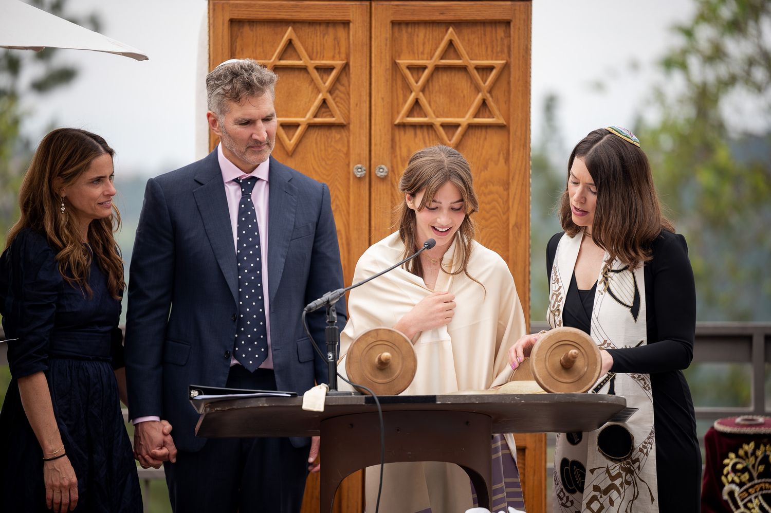 A Bar Mitzvah celebration at a synagogue with people gathered around the Torah scrolls during the ceremonial reading.