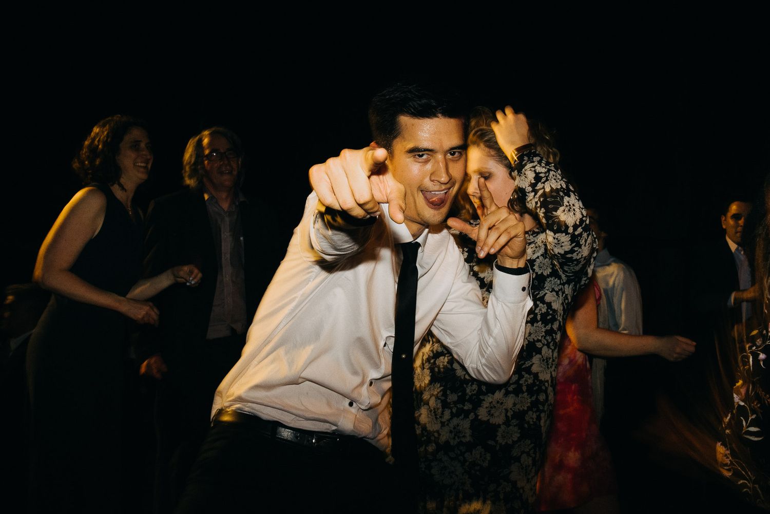 Two people dancing energetically together at a dark party or nightclub event.