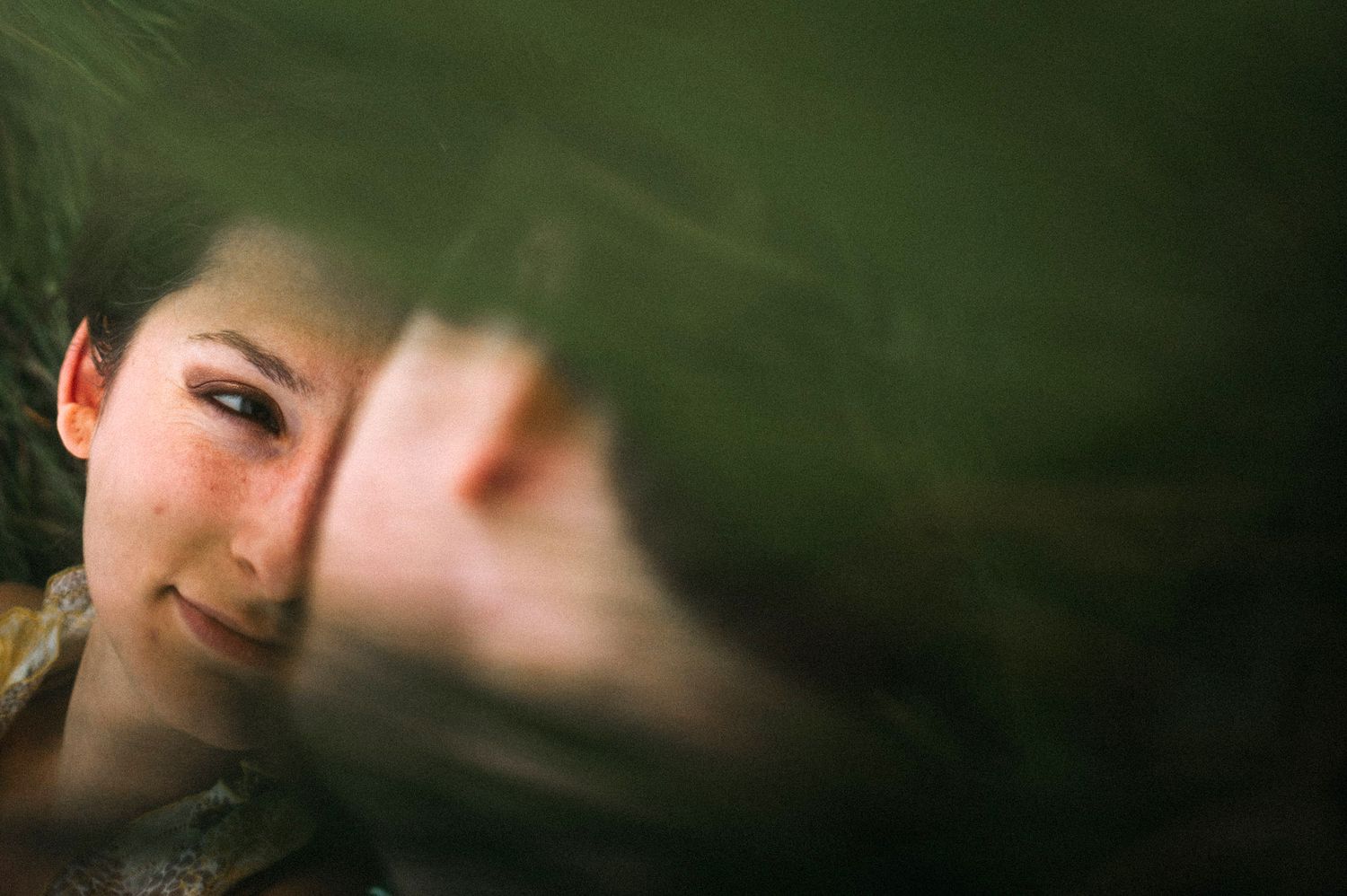 Close-up photo of someone looking at the camera with a blurry foreground element creating a dreamy effect.